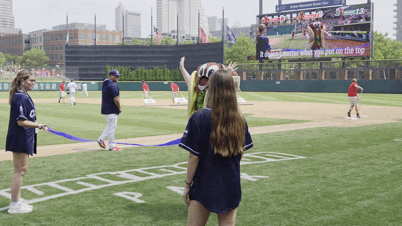 A gif of Alissa winning the hot dog race, passing through the finish line tape with her hands in the air, and then jumping up and down.