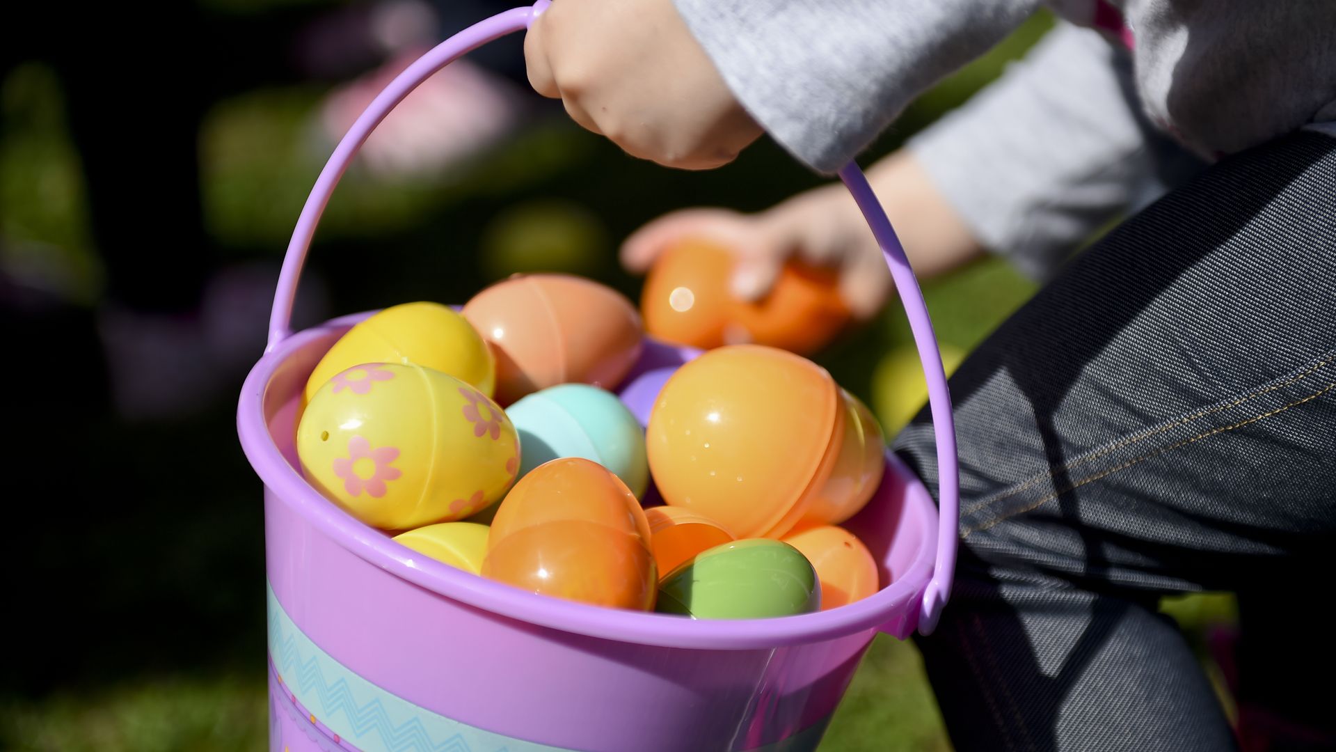 A child's hand holds a basket of plastic easter eggs