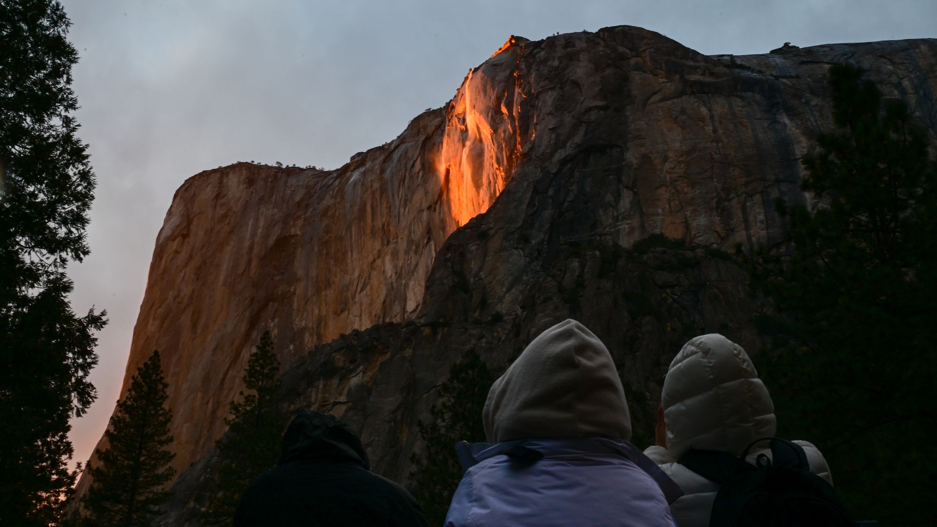 Photo of three people looking at a waterfall at Yosemite