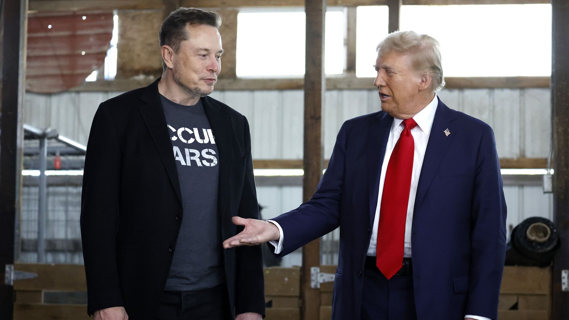  Republican presidential nominee, former President Donald Trump offers his hand to Elon Musk back stage during a campaign rally at the Butler Farm Show grounds on October 05, 2024 in Butler, Pennsylvania. 