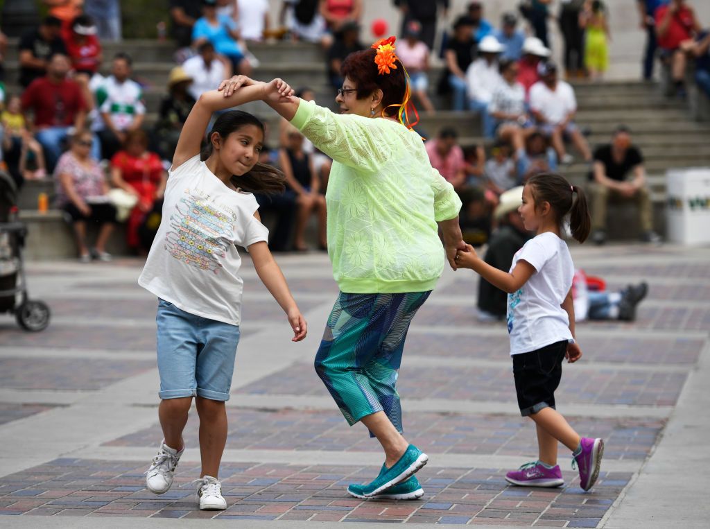 Diane Kawamura, center, dances to mariachi music with her two nieces at the 30th annual Cinco de Mayo "Celebrate Culture Festival" May 6, 2017 in Denver, Colorado. 