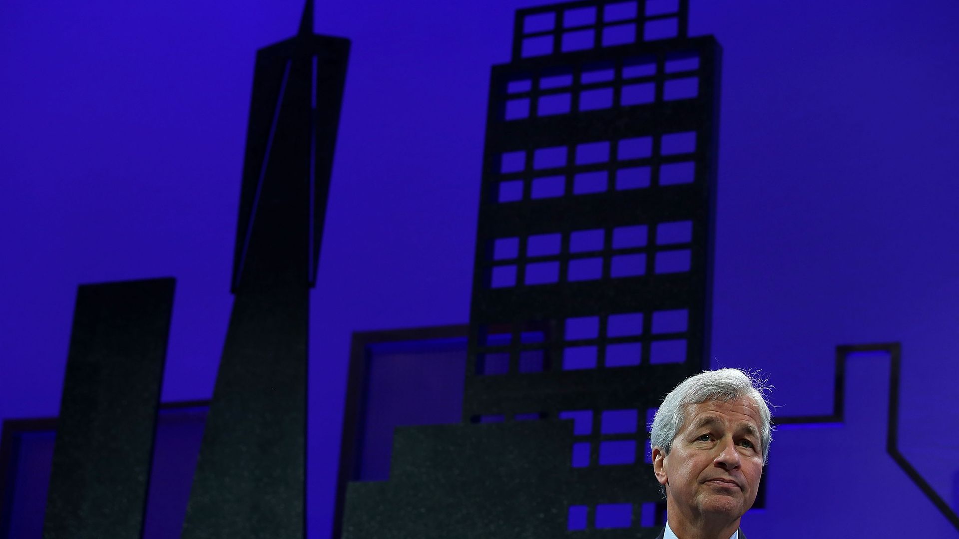 A photo of JPMorgan CEO Jamie Dimon with a cityscape in the background.
