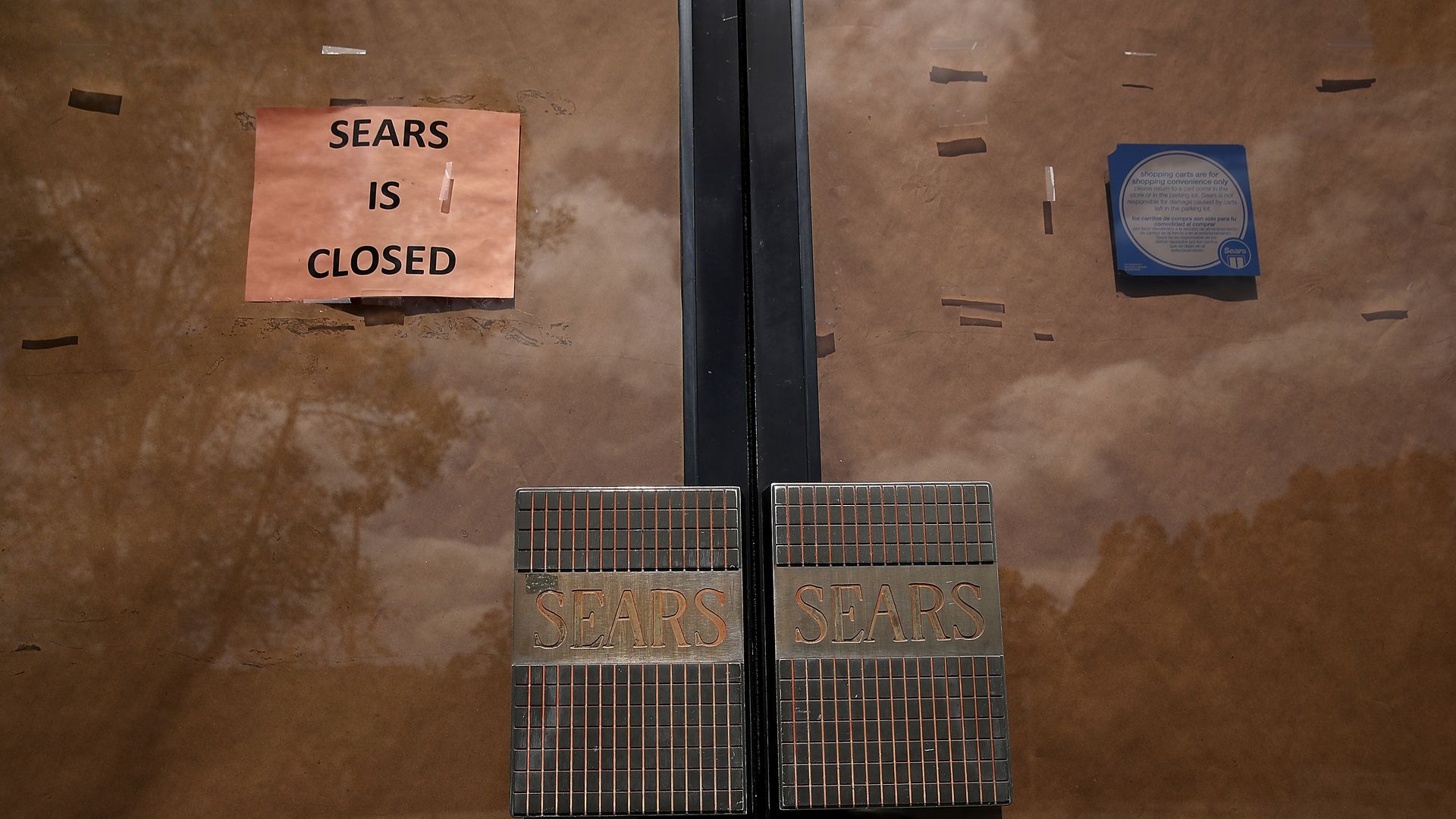 A "closed" sign pasted over Sears' papered-over front doors