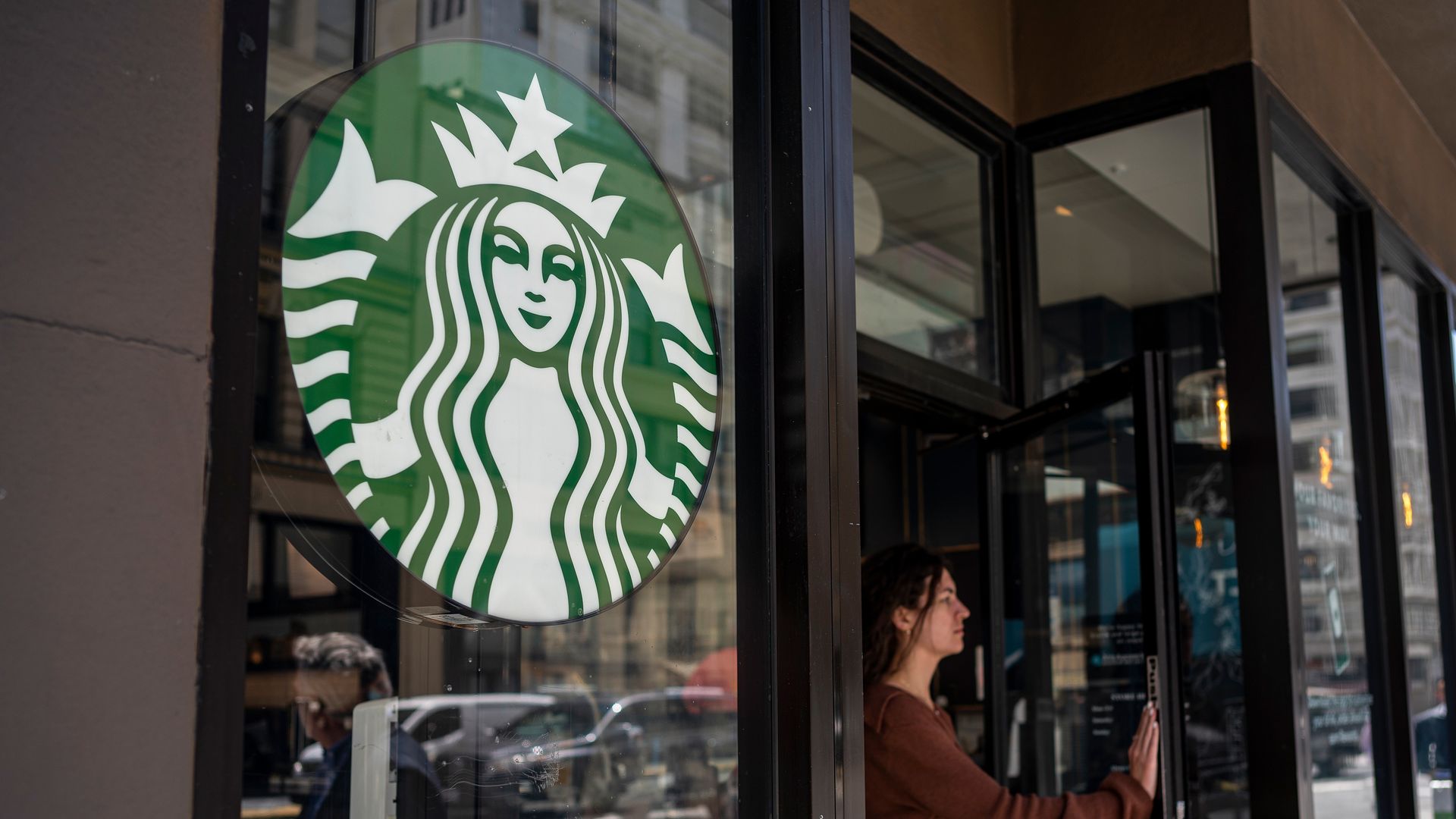 Picture of the Starbucks logo in a location, with a person walking out