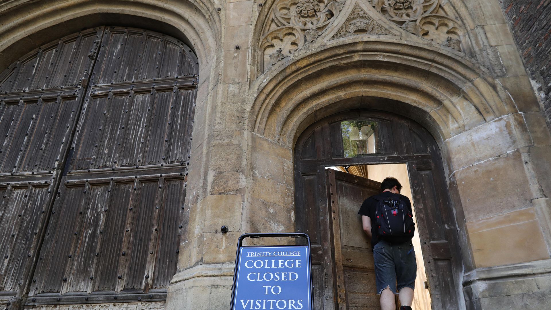 A student wearing a backpack walks through an ornate doorway 