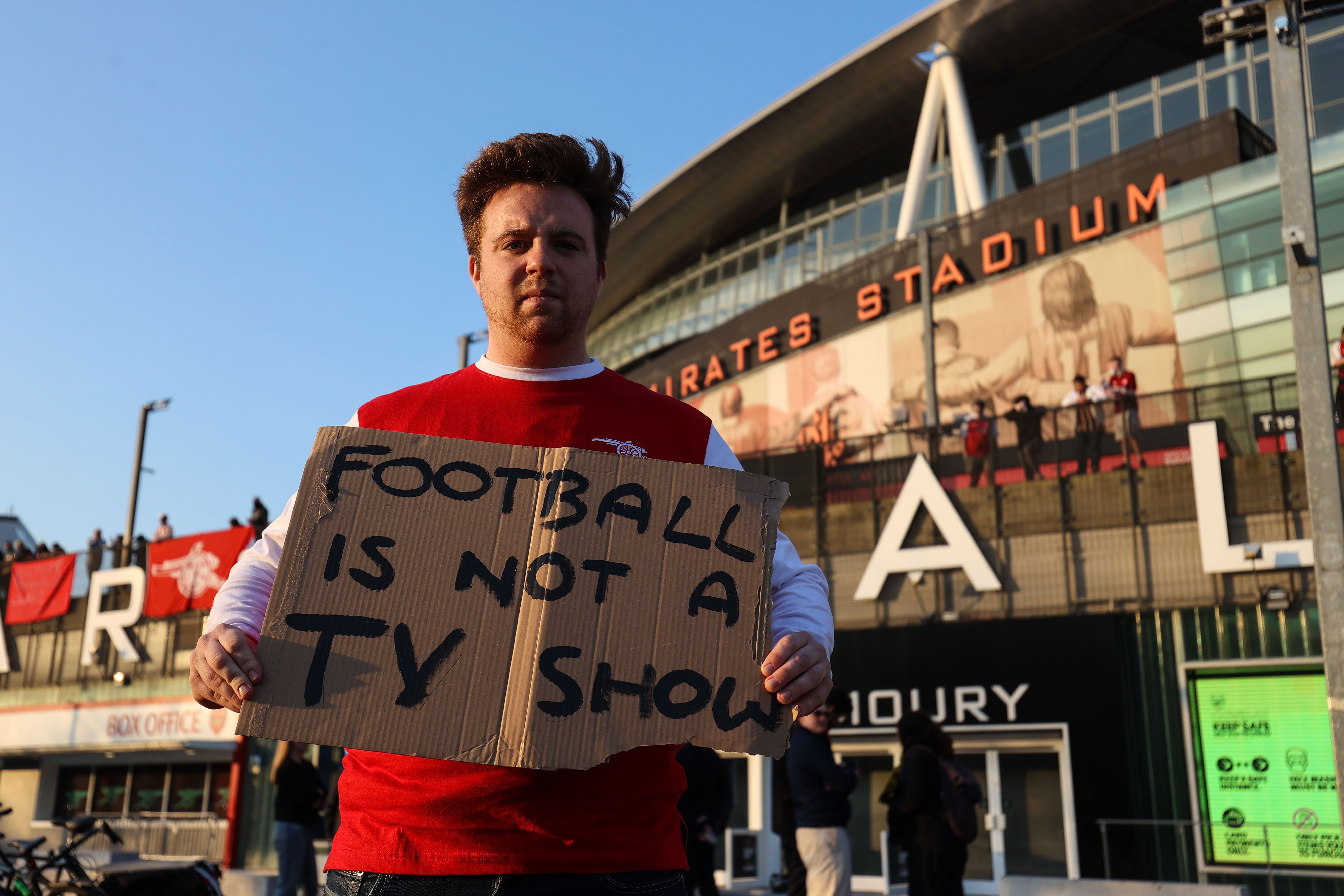 Picture of a man holding a sign that says "Football is not a TV show"