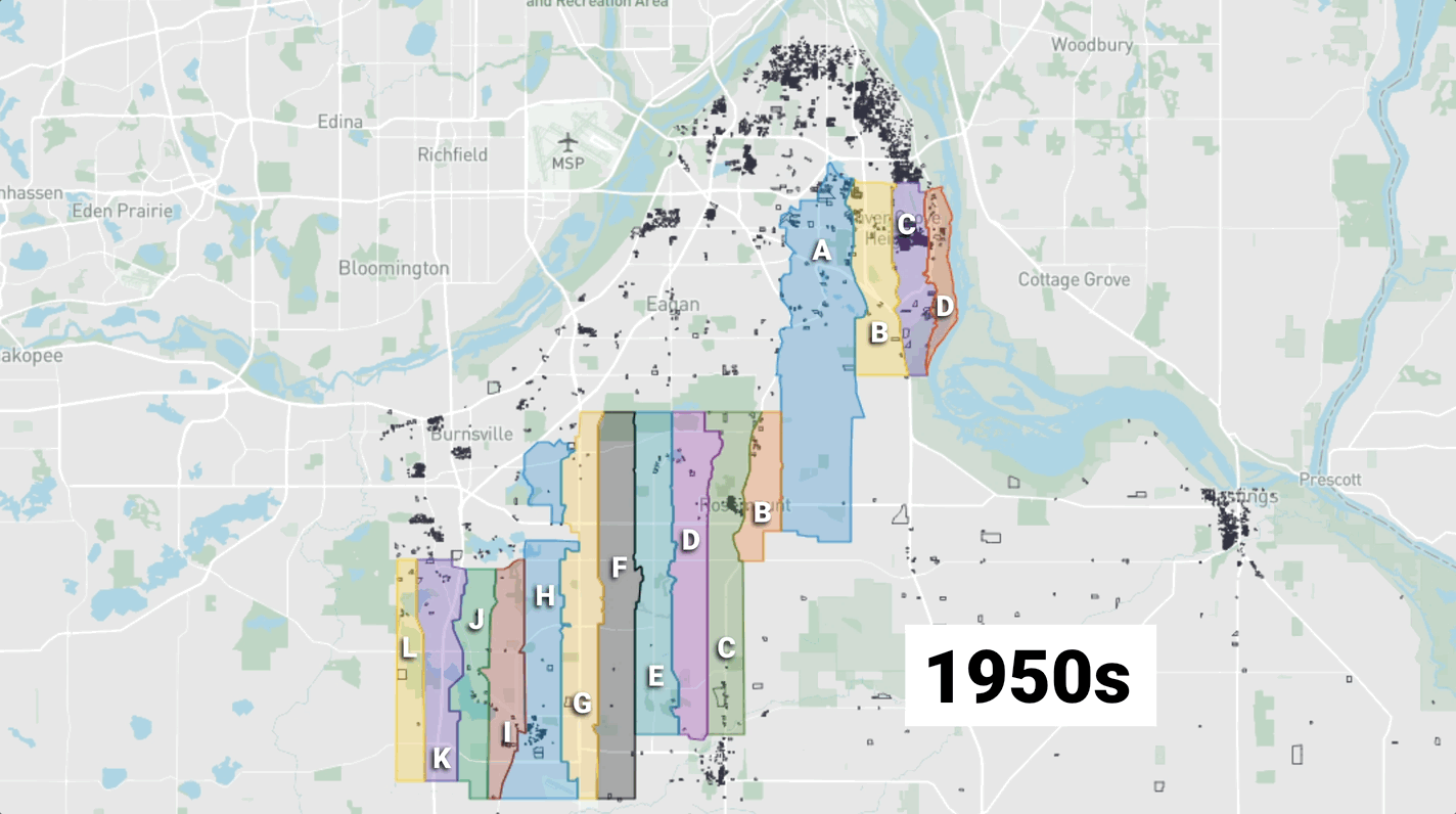 Map of the Minneapolis–Saint Paul area with vertical color blocks A–L along the Mississippi River; each block a different color. As the animation progresses, parcels animate in the decade in which they were built, as denoted by a new decade label from '1950s' to '2020s.'