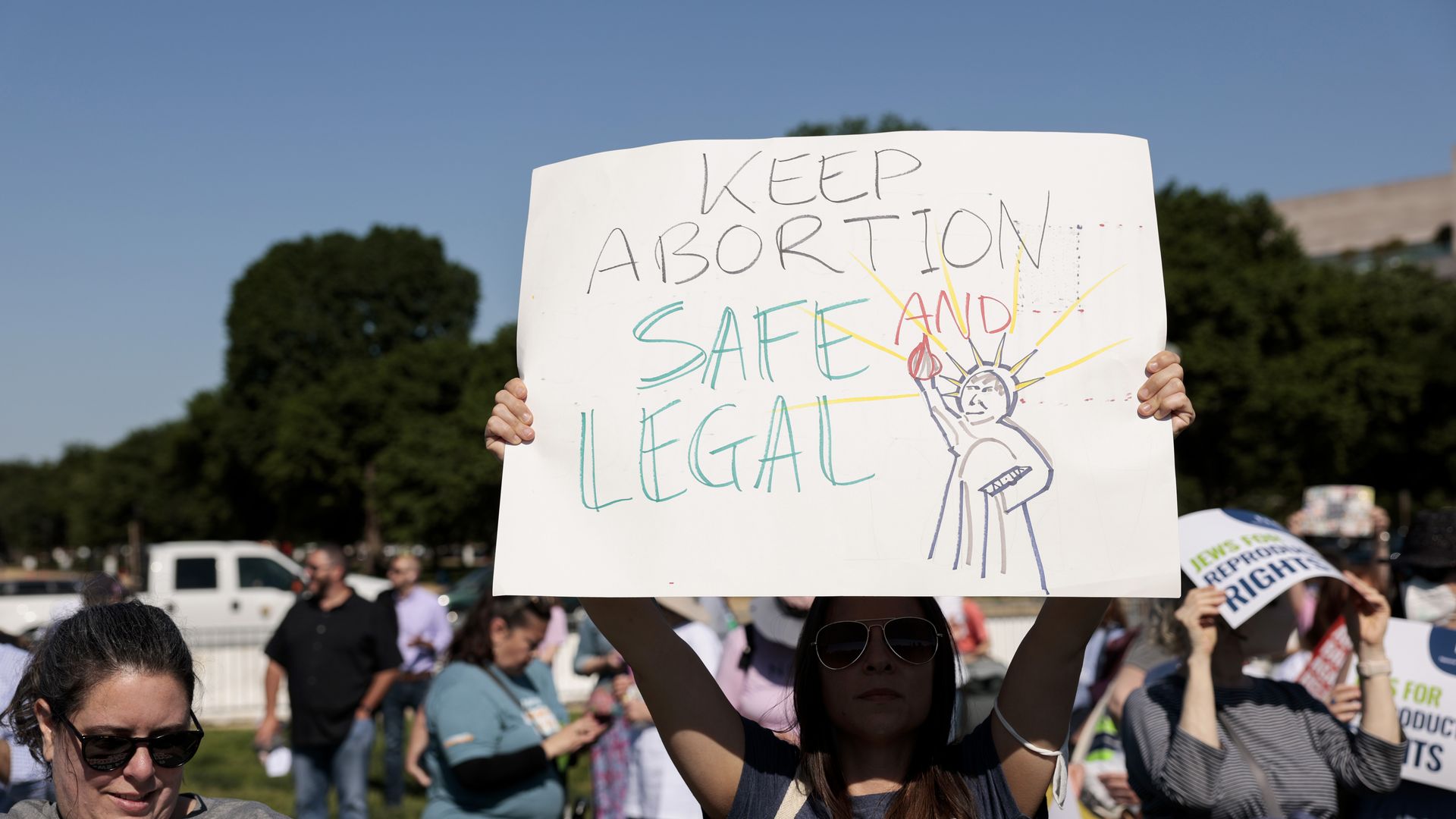 Picture of a person holding a sign that says "keep abortion safe and legal"