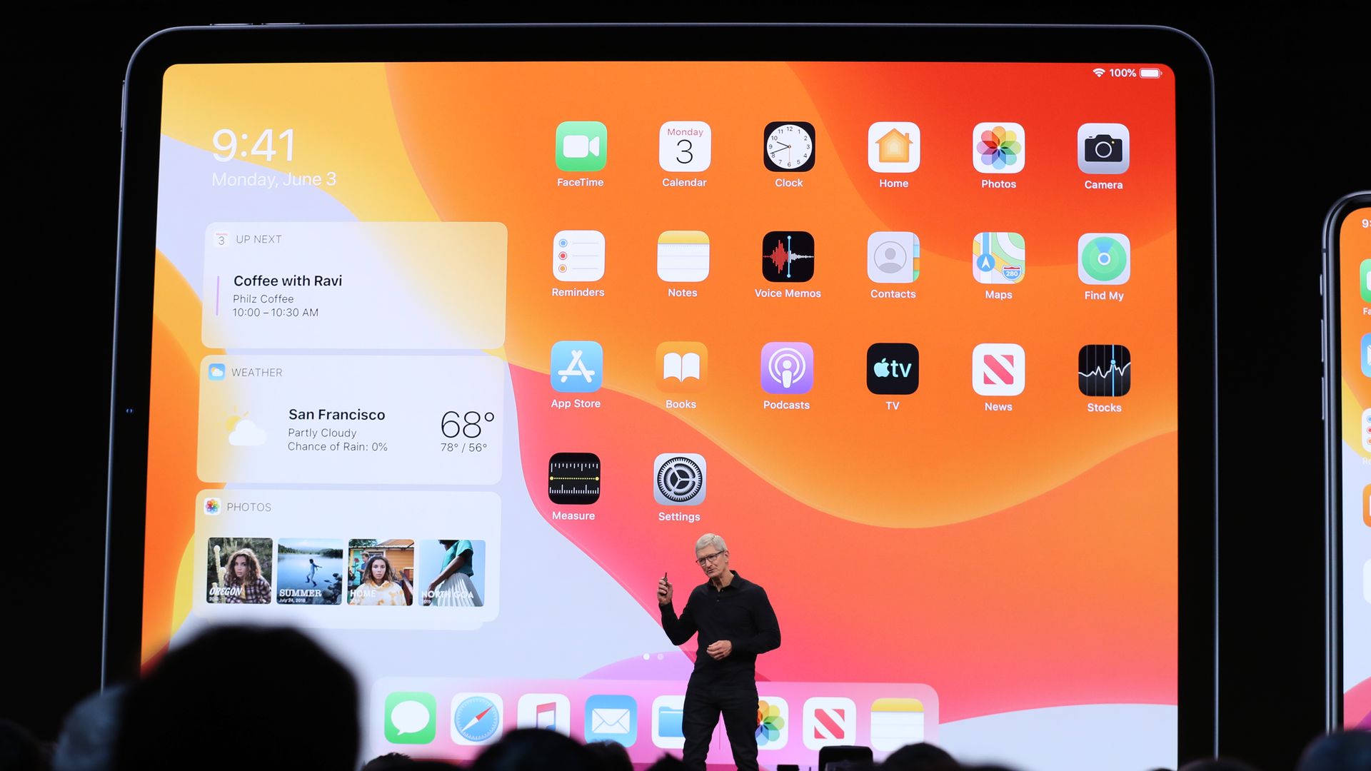 In this image, Tim Cook stands in front of a giant screen shot of an Apple product.