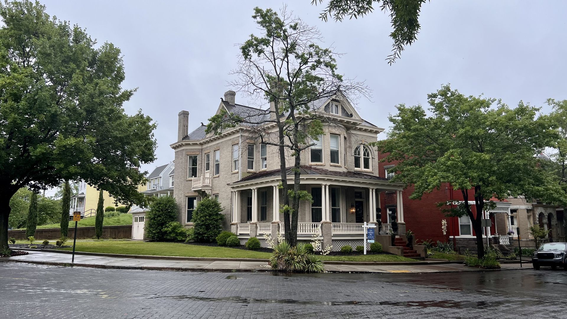 A Victorian-style house surrounded by trees and a sidewalk