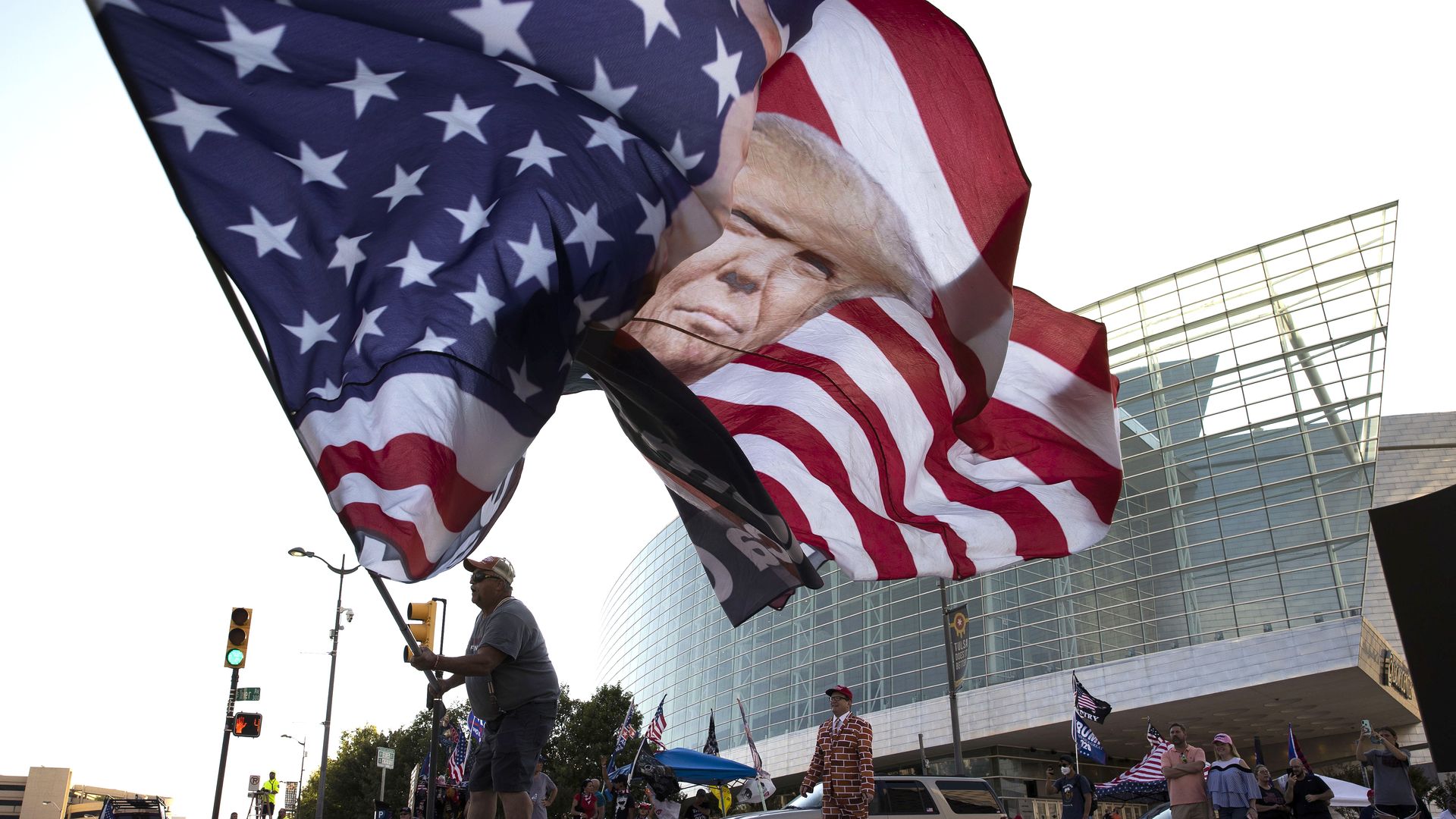 A man waves a huge American flag with President Trump's face on it outside the BOK Center in Tulsa, Oklahoma