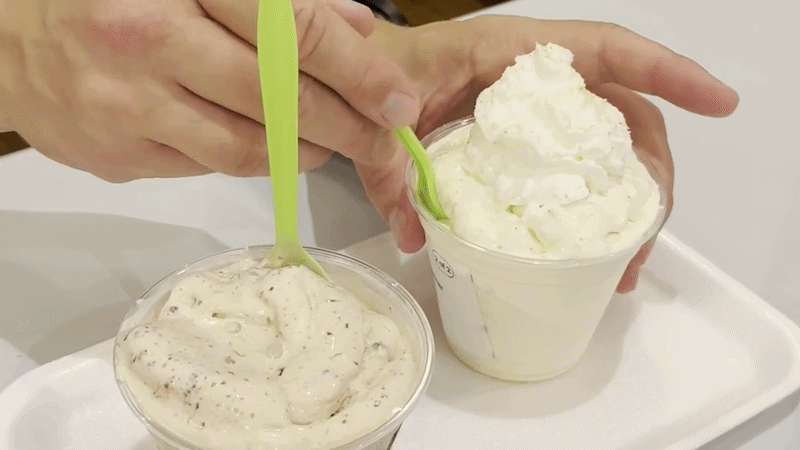 A hand pulls a spoon full of vanilla frozen custard from a cup.