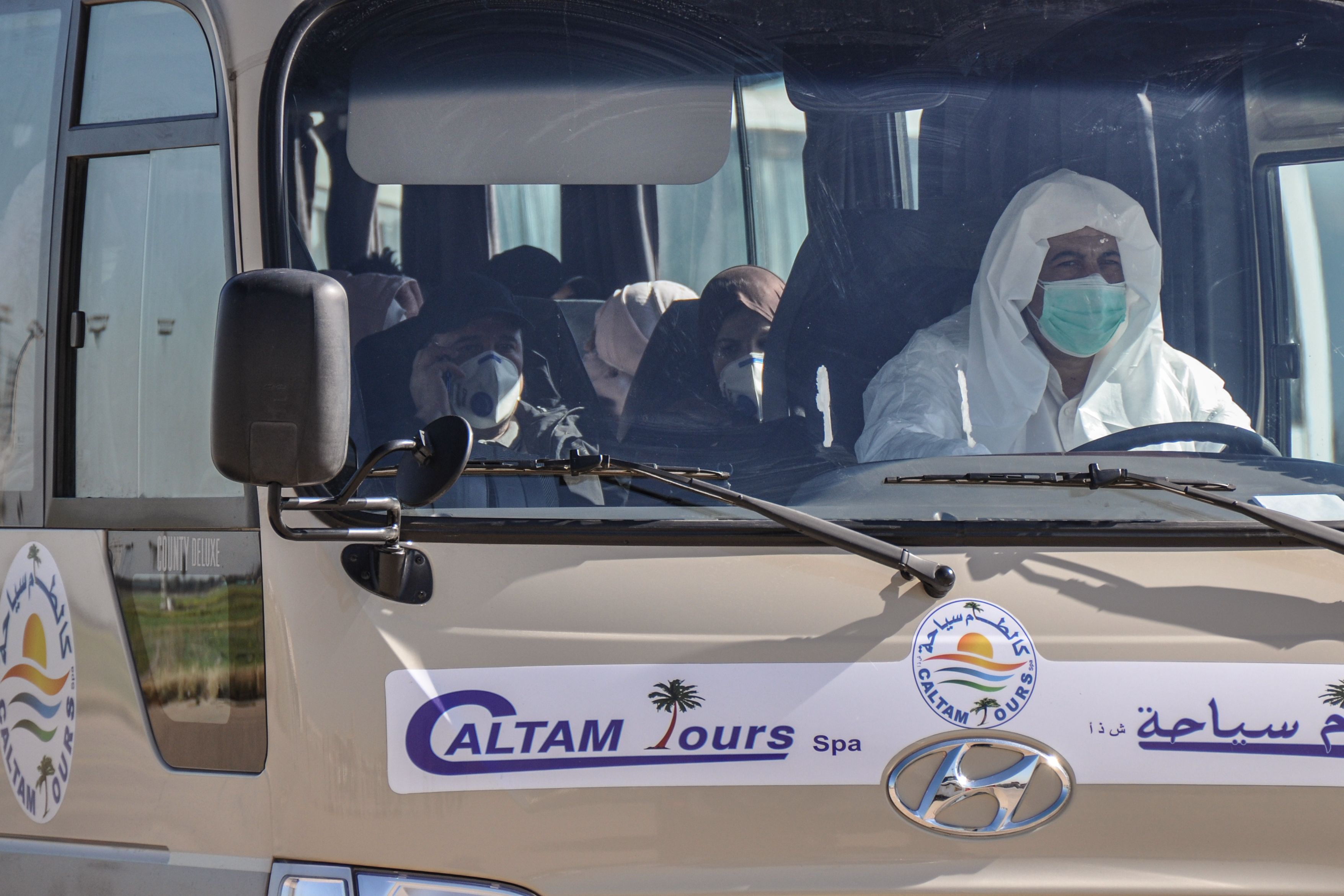 Passengers leave on a bus at the the Houari Boumediene Airport, after arriving on an Algerian air plane following their evacuation from China 