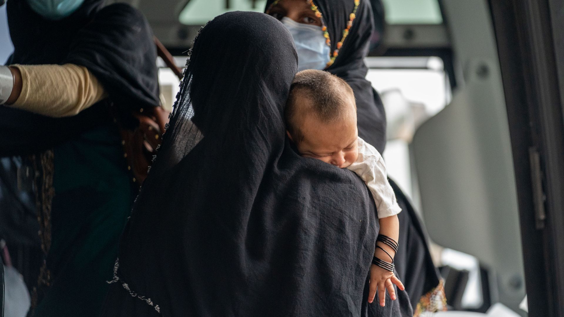 An Afghan refugee holding a sleeping baby at Dulles Airport