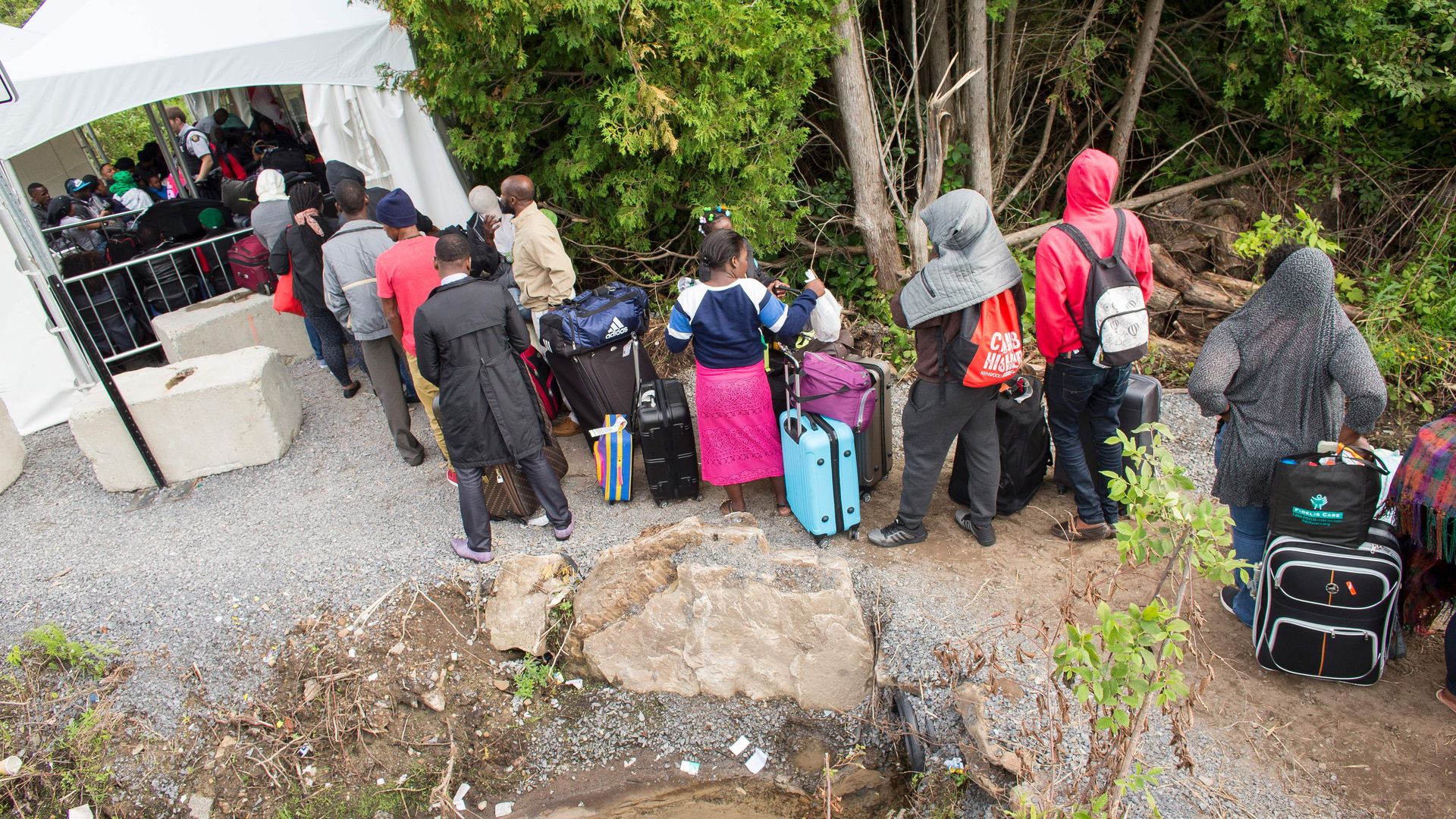 A long line of asylum seekers wait to illegally cross the Canada/US border near Champlain, New York