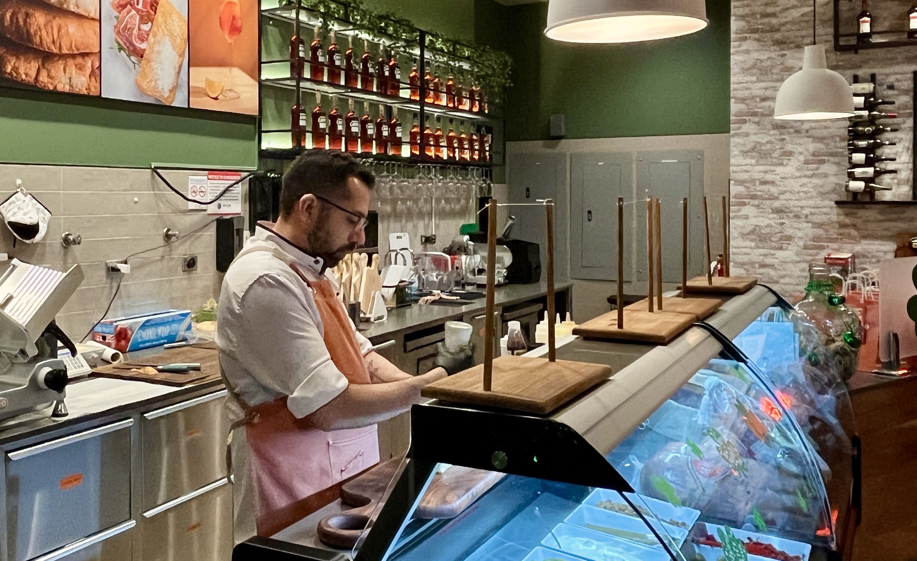 guy making a sandwich behind a deli counter