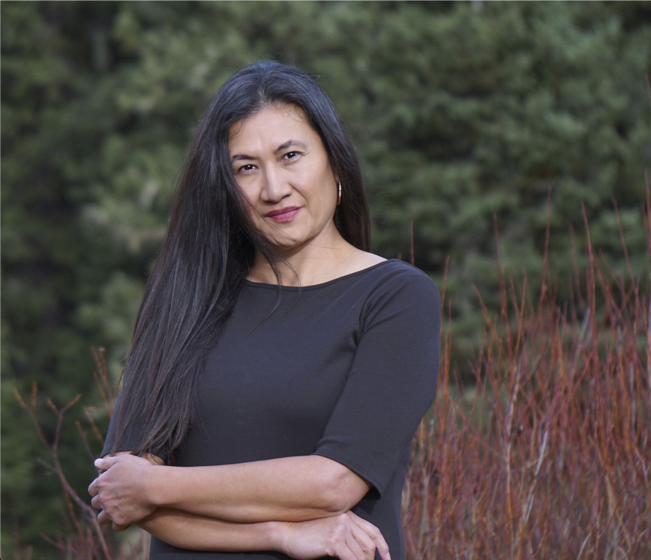 A woman stands in front of trees