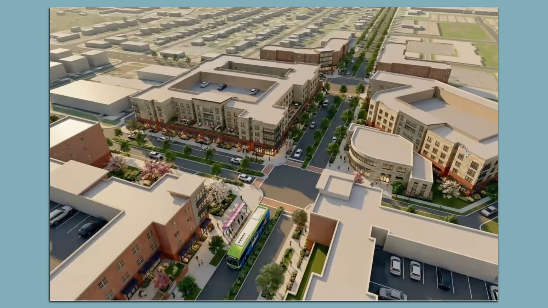 Aerial view of a planned urban district: beige, multi-story buildings along a tree-lined street with ground-floor shops, parked cars, a bus, and a central plaza amid surrounding blocks.