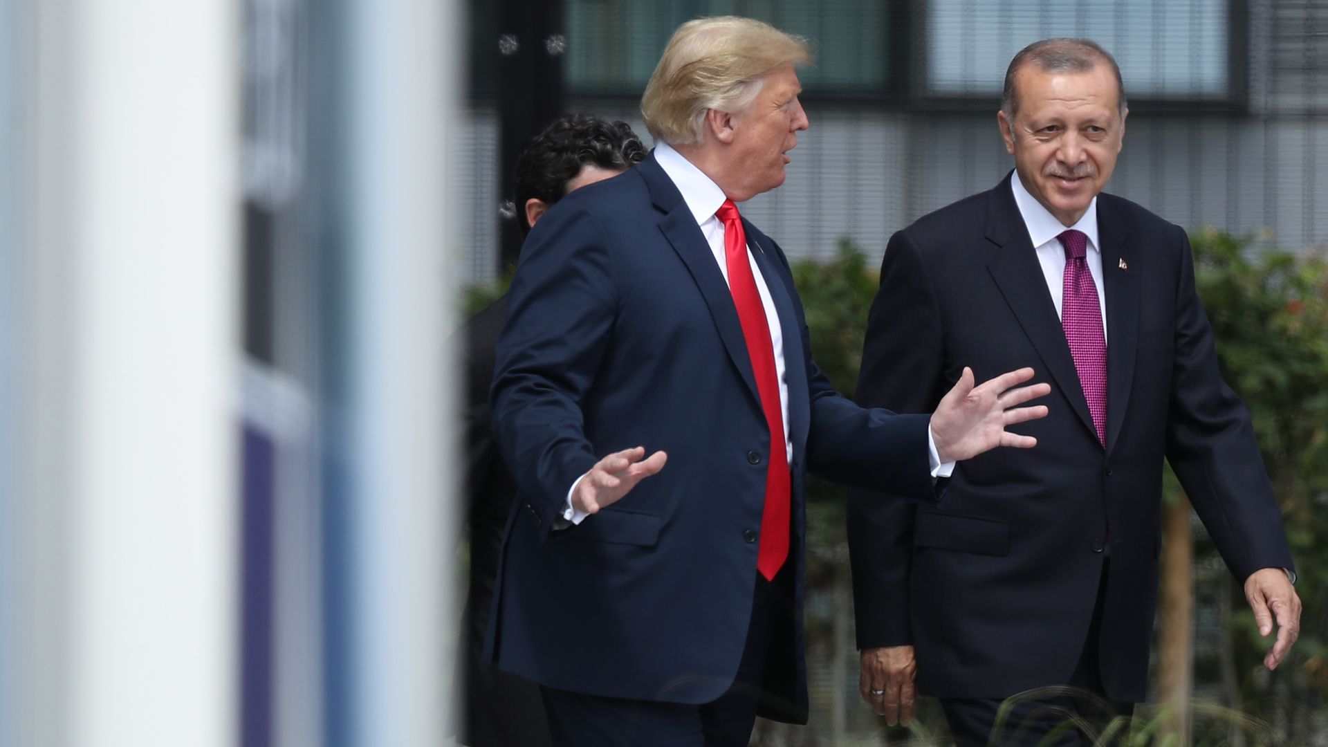 In this image, Trump and Erdogan walk together outside while talking, both wearing suits.