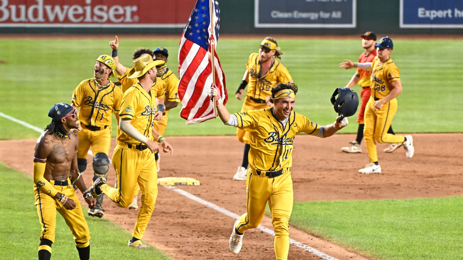 A photo of baseball players in yellow uniforms running on a baseball field. 