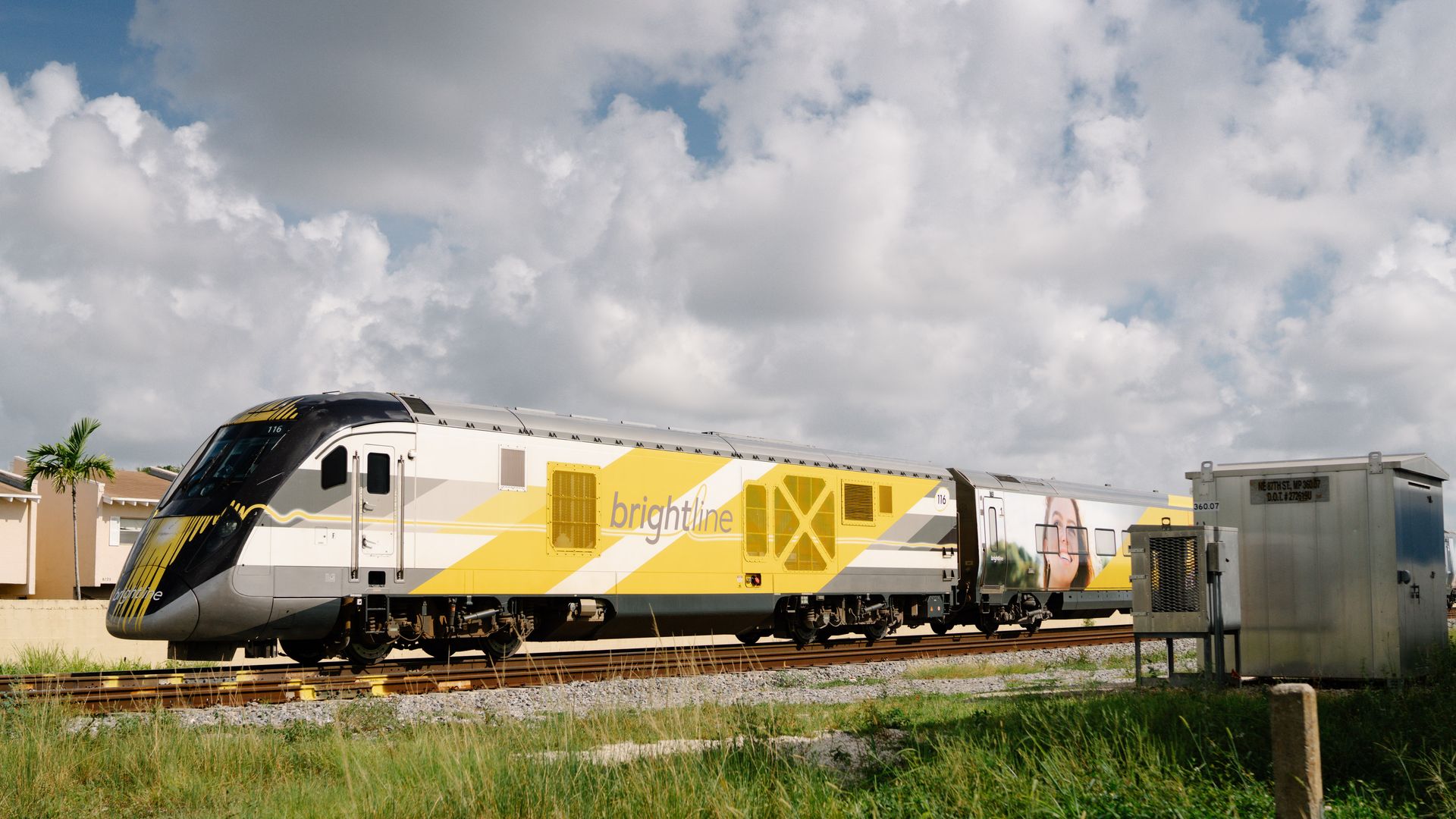 A yellow, white and black Brightline train on the track