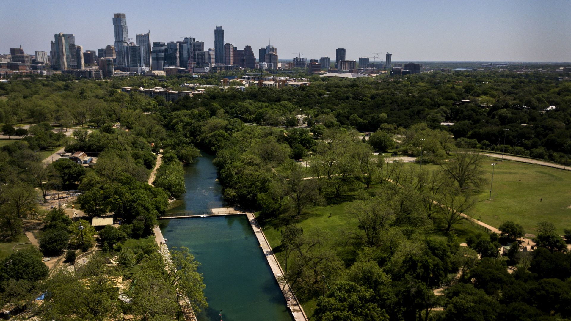 Barton Springs pool in the foreground with the Austin skyline in the background.