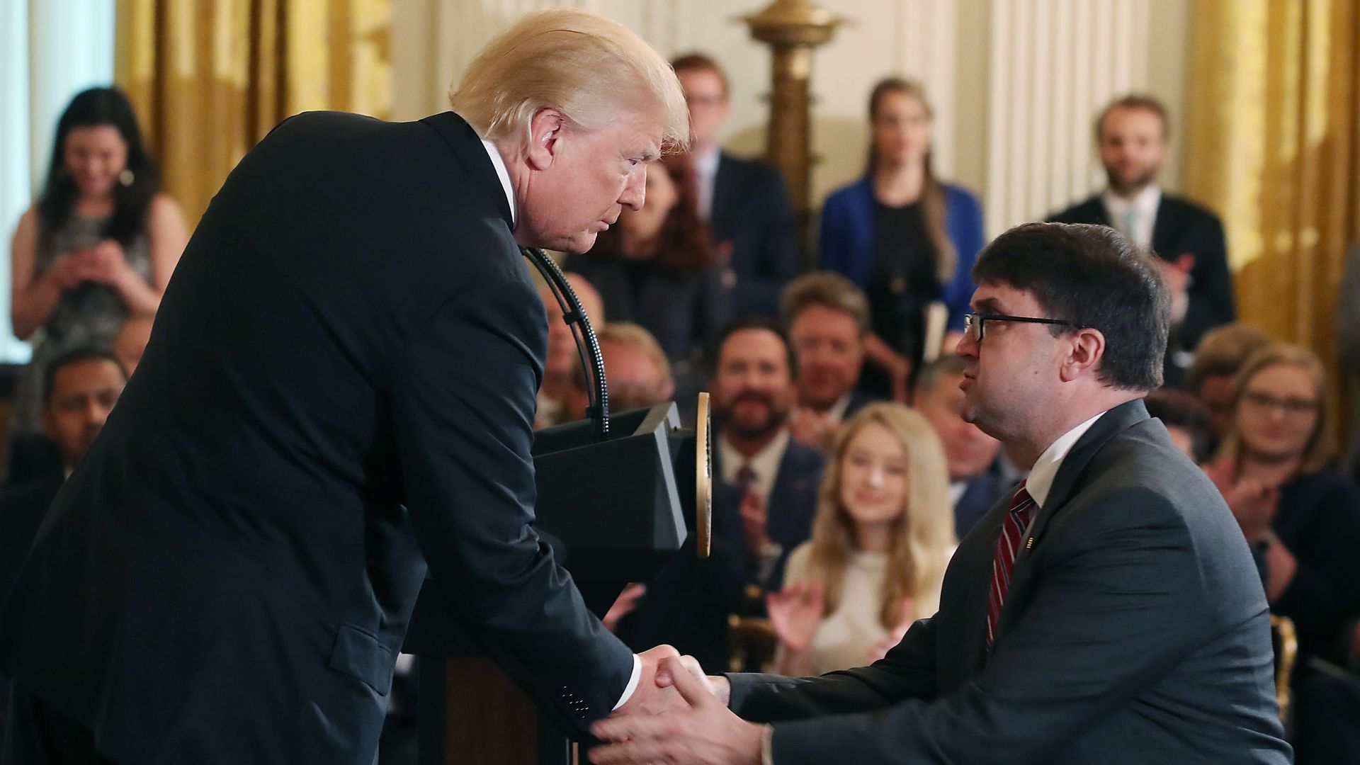 President Donald Trump leans down to shake hands with Robert Wilkie after nominating him to be next Veterans Affairs Secretary, during an event in the East Room at the White House