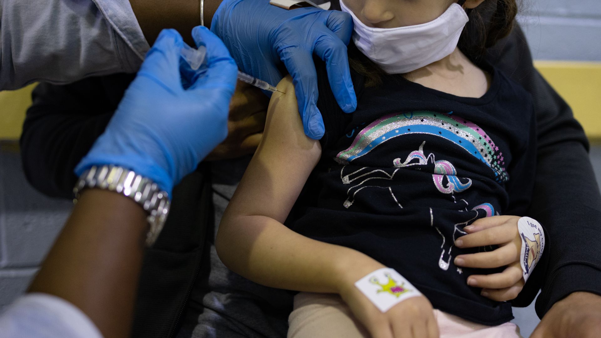Photo of a health care worker administering a vaccine shot to a young child