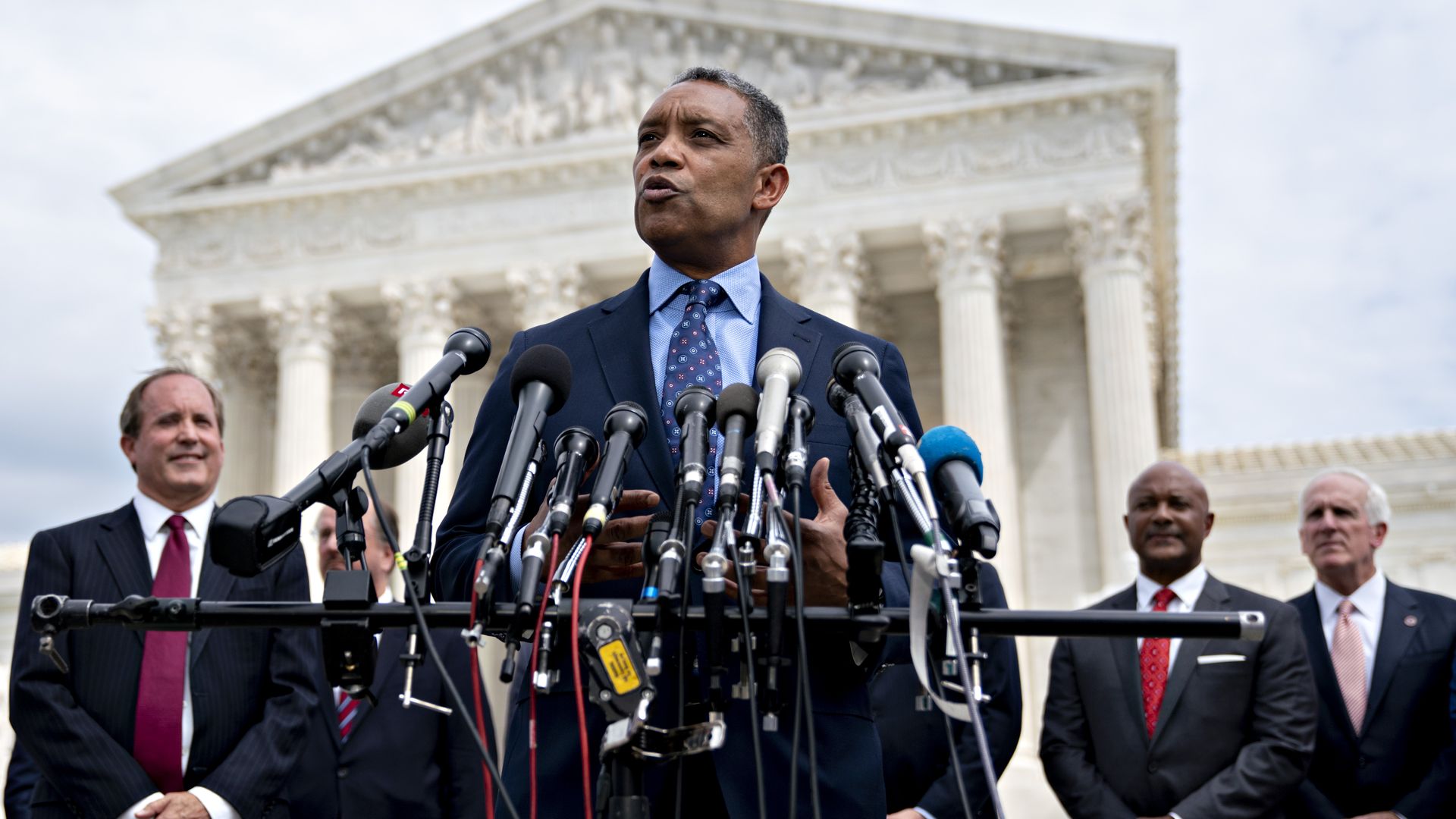 Karl Racine stands before microphones at a press conference