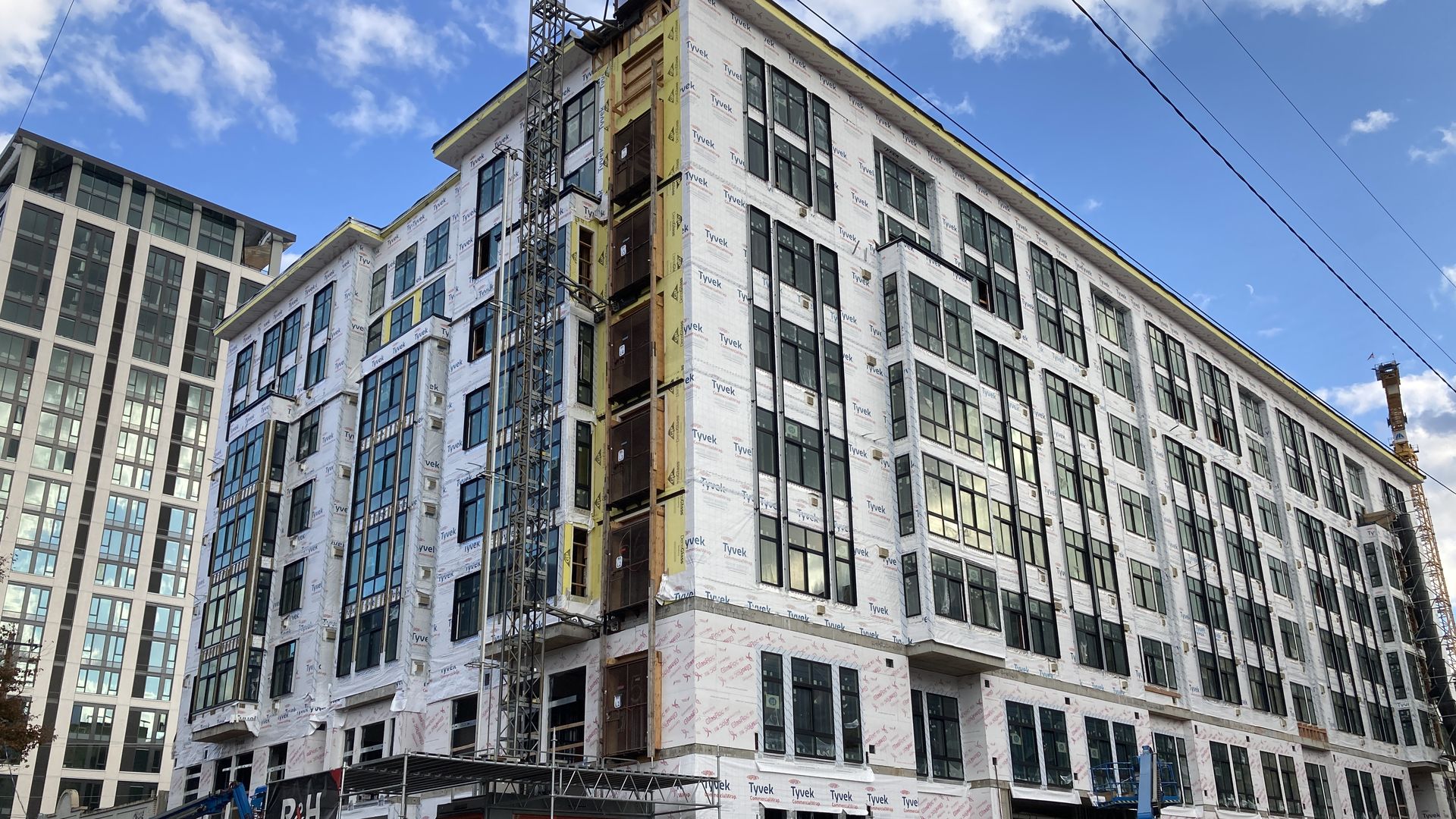 A building under construction, wrapped in white Tyvek.