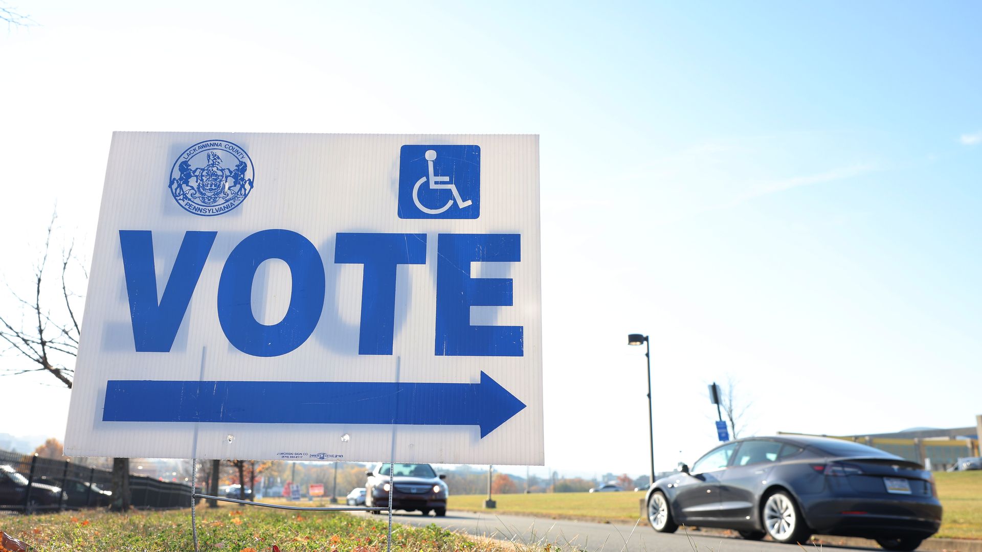A sign posted in grass points to where the voting place is