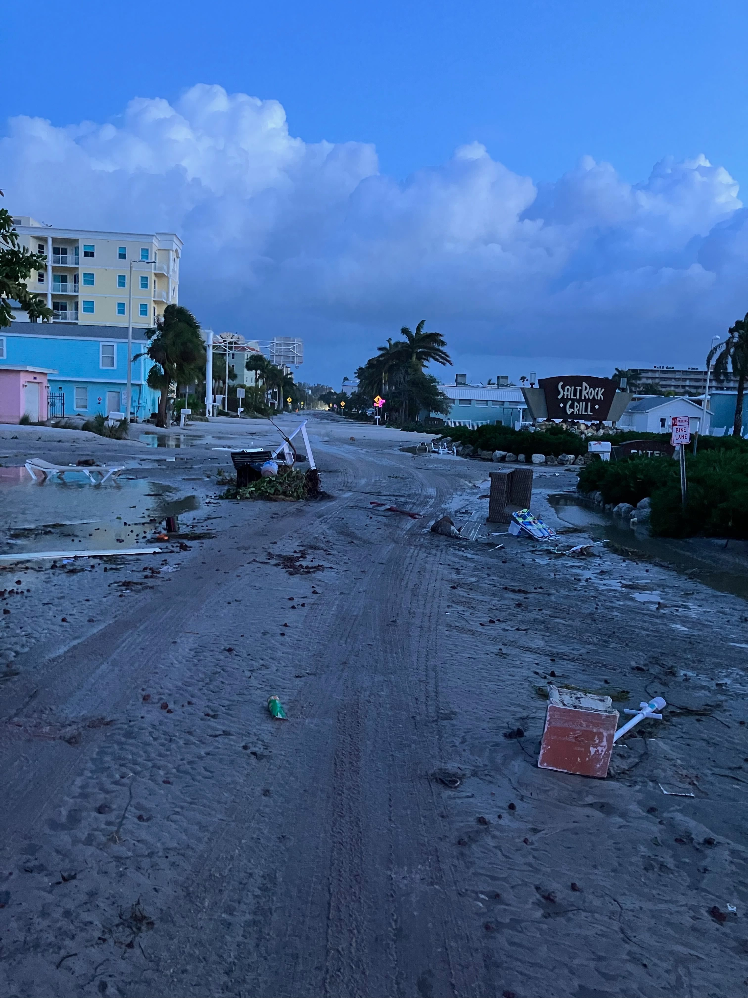 Wreckage in Indian Shores: signs and debris fill a sandy street.