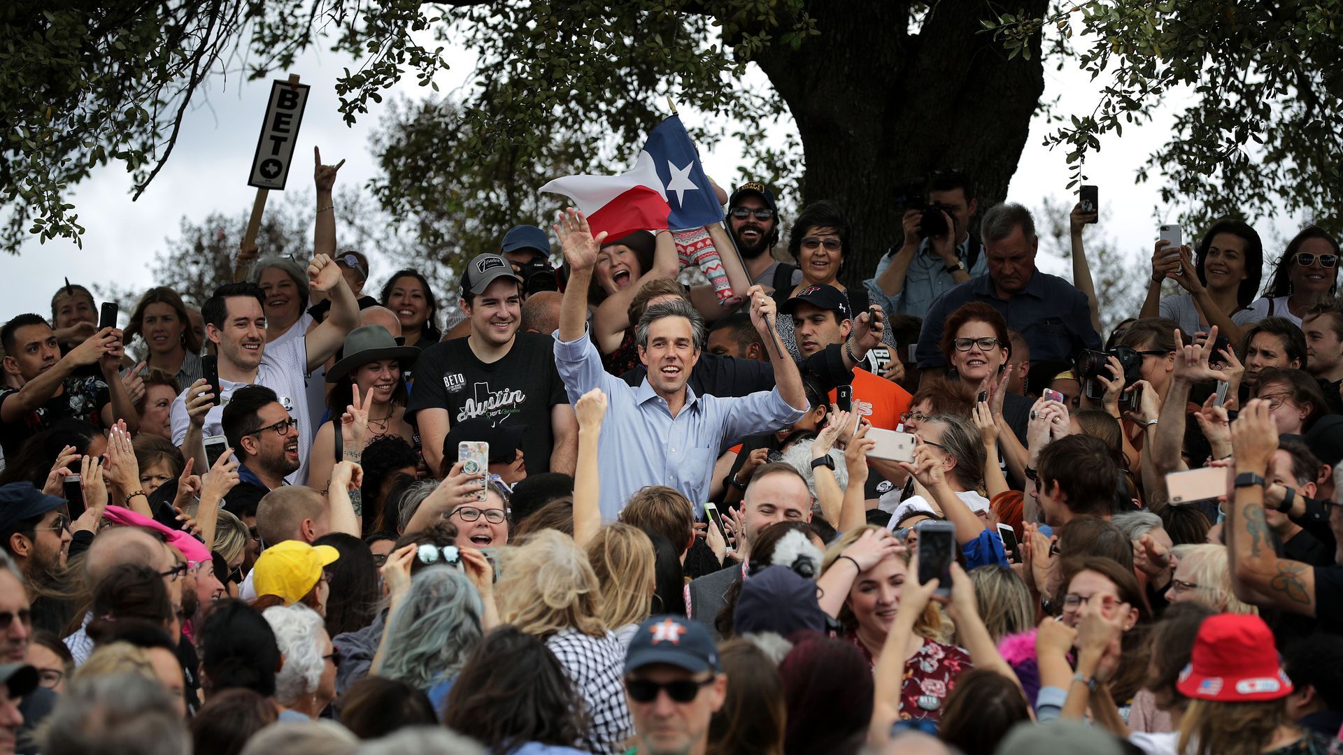 A photo of Beto O'Rourke holding a Texas flag in a crowd of people.