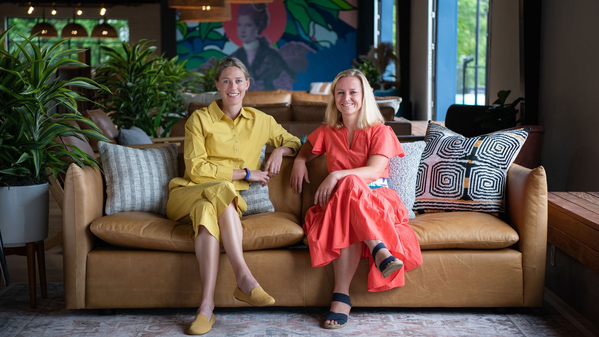 two women sit side-by-side on a couch