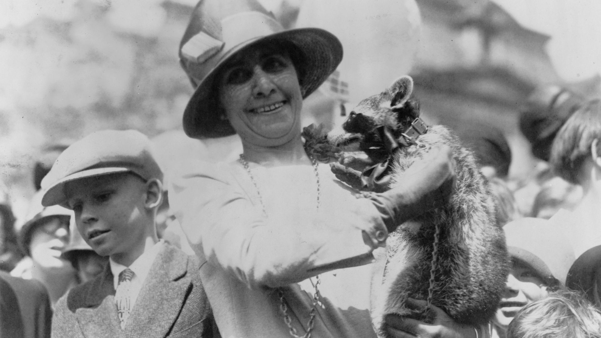 US First Lady Grace Coolidge (1879 - 1957) holds up her pet raccoon, Rebecca, for a crowd of children at the annual White House Easter Egg Roll, Washington DC, April 18, 1927. (Photo by Herbert French/PhotoQuest/Getty Images)