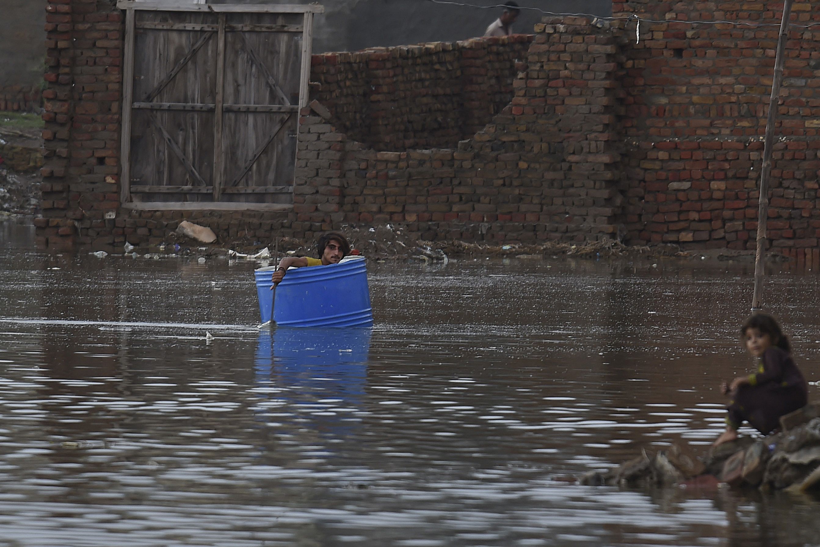 A man uses a plastic drum to cross a flooded area after heavy monsoon rains in Jacobabad, Sindh province, on August 26.