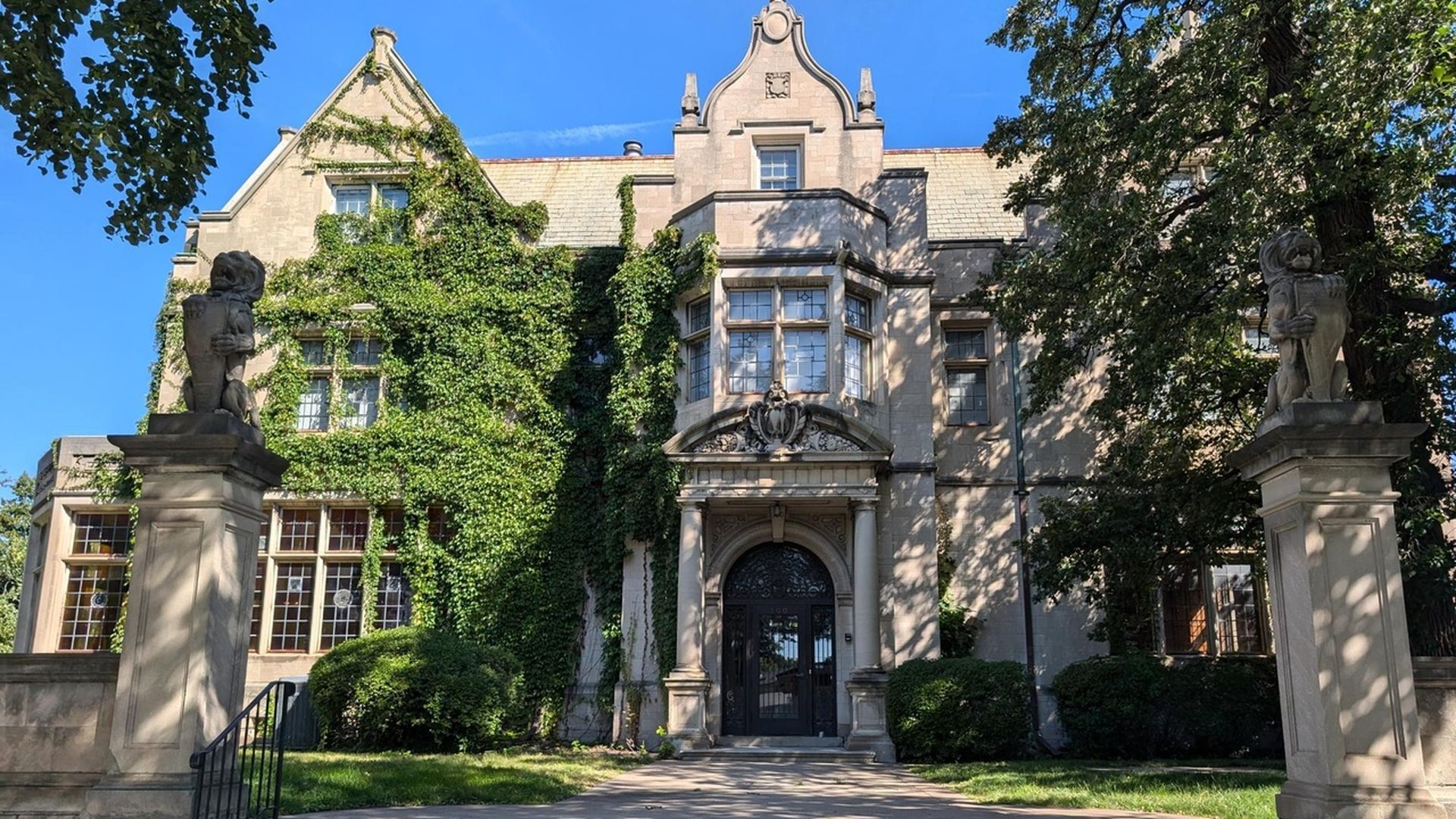 The exterior of a limestone mansion covered in ivy.