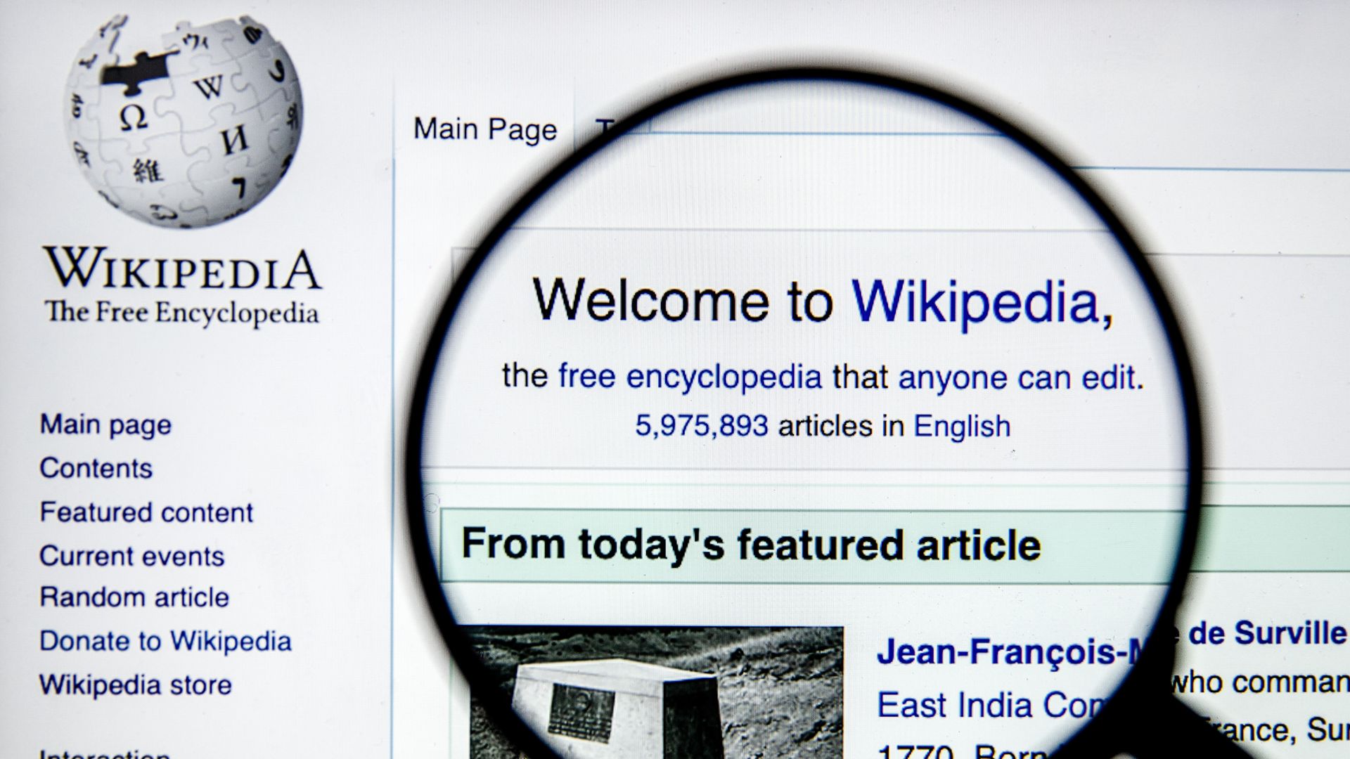 Wikipedia's front page under a magnifying glass.