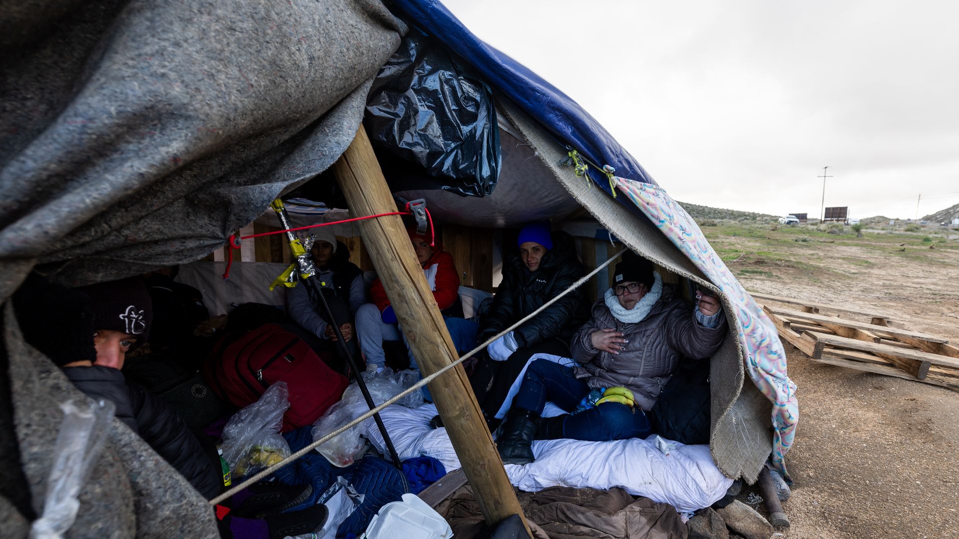 Asylum seekers sit inside a tent as they wait to be processed by border patrol agents at an improvised camp near the US-Mexico border on February 7, 2024 in Jacumba Hot Springs, California. 