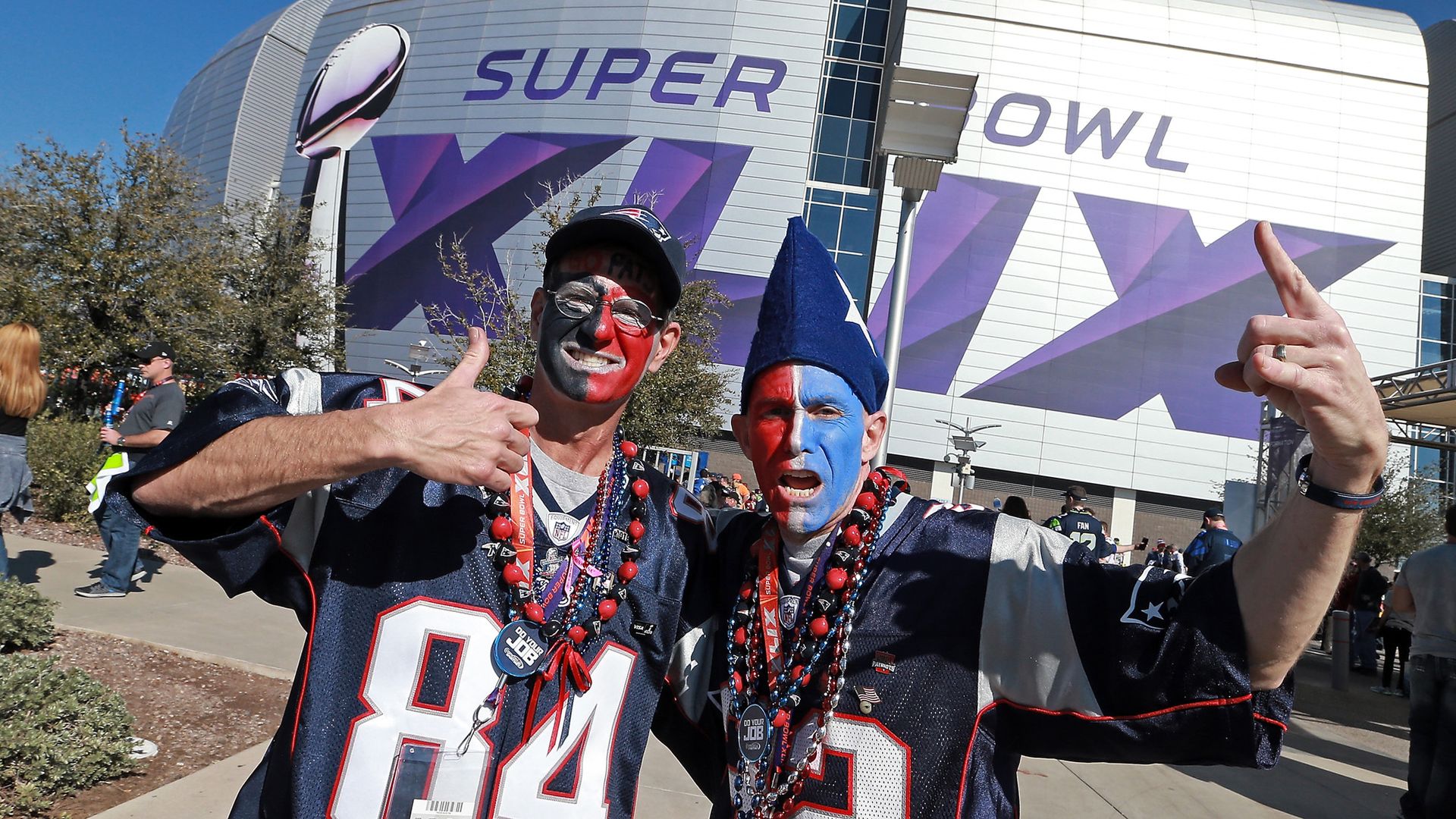 Two Patriots fans in front of a football stadium.