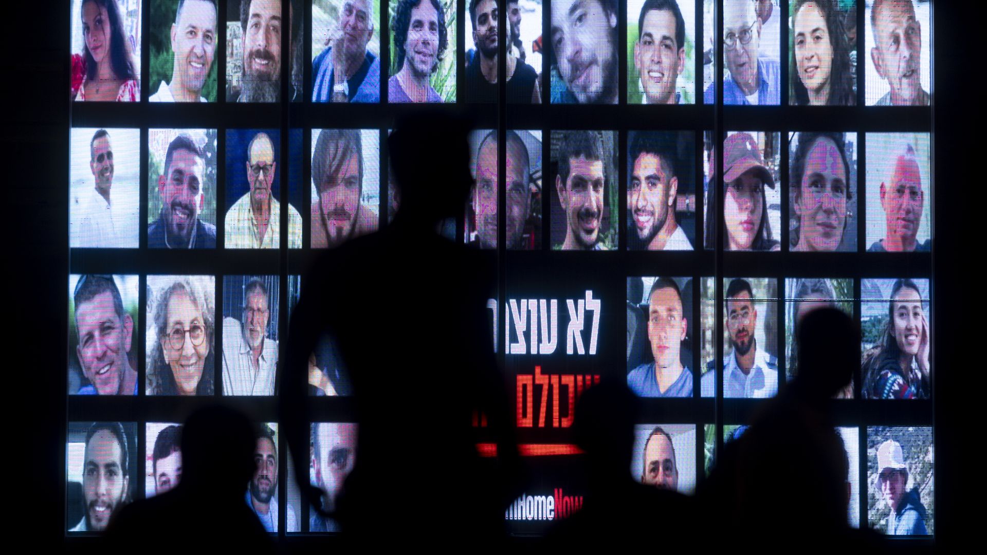 People walk by a screen displaying photos of hostages kidnaped on Oct 7 Hamas deadly attack outside a presser by Secretary of State Antony Blinken on August 19, 2024 in Tel Aviv, Israel. 