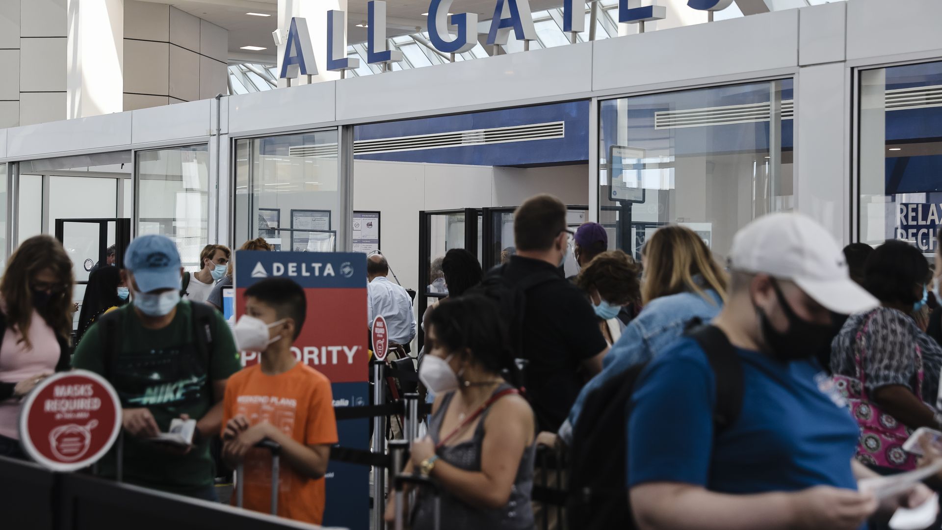 Travelers wearing protective face masks wait in line at a Transportation Security Administration (TSA) screening at LaGuardia Airport (LGA) in New York, U.S., on Monday, Aug. 2, 2021.