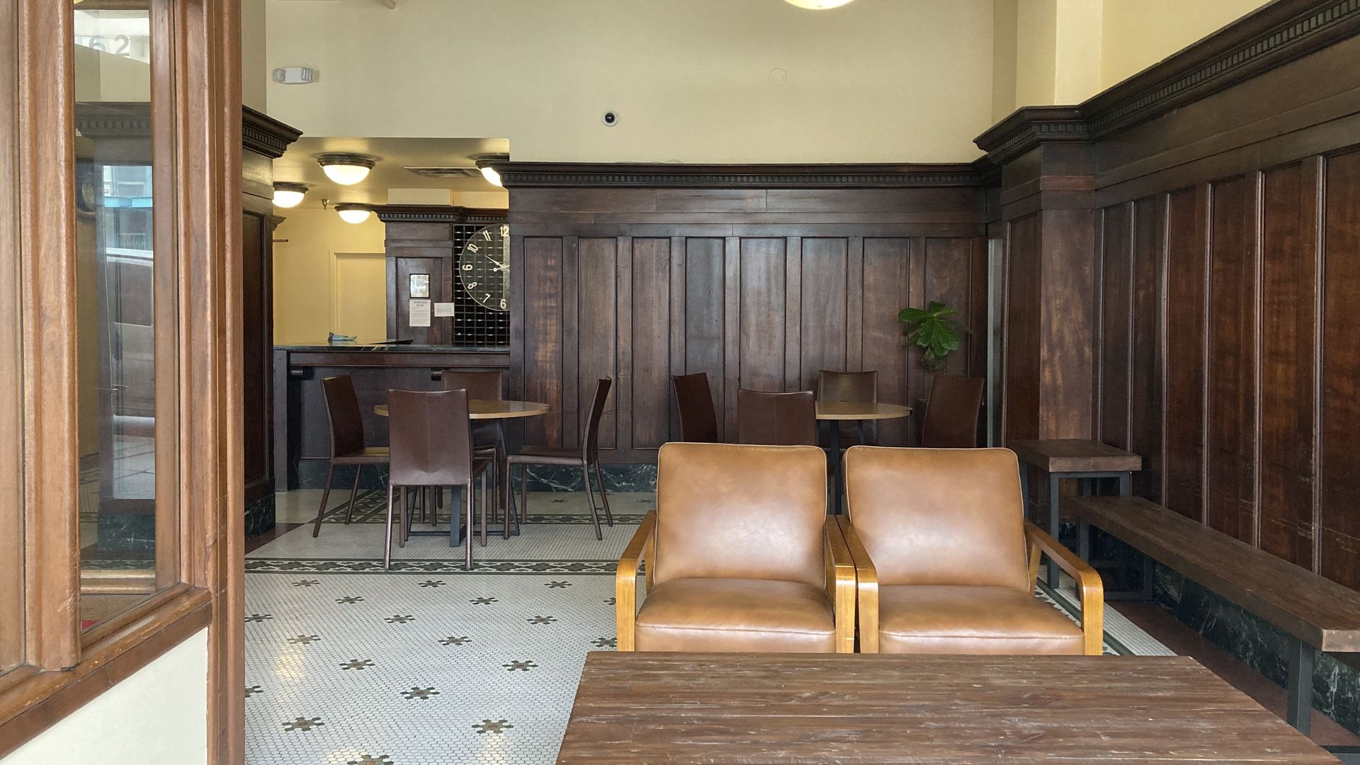 The lobby of a building with leather chairs and dark wood paneling. 