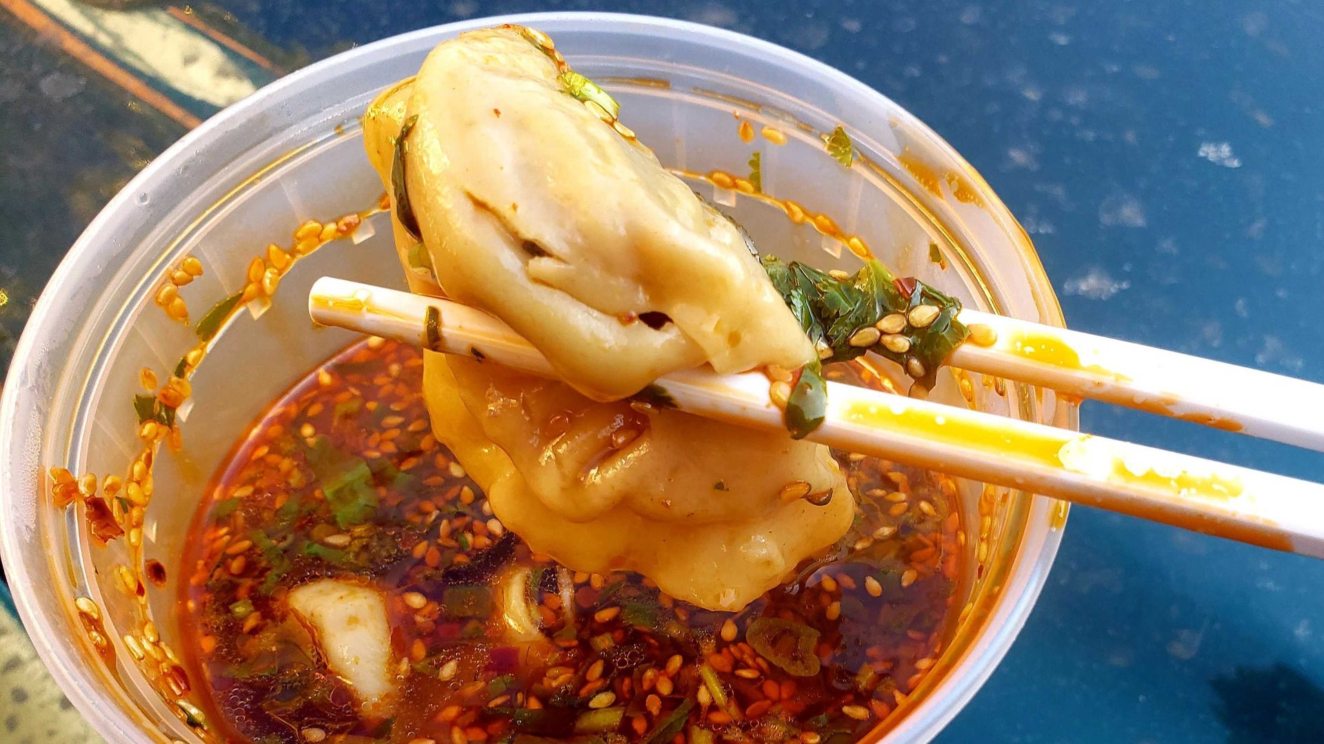 Photo of a dumpling being dipped in sauce. 