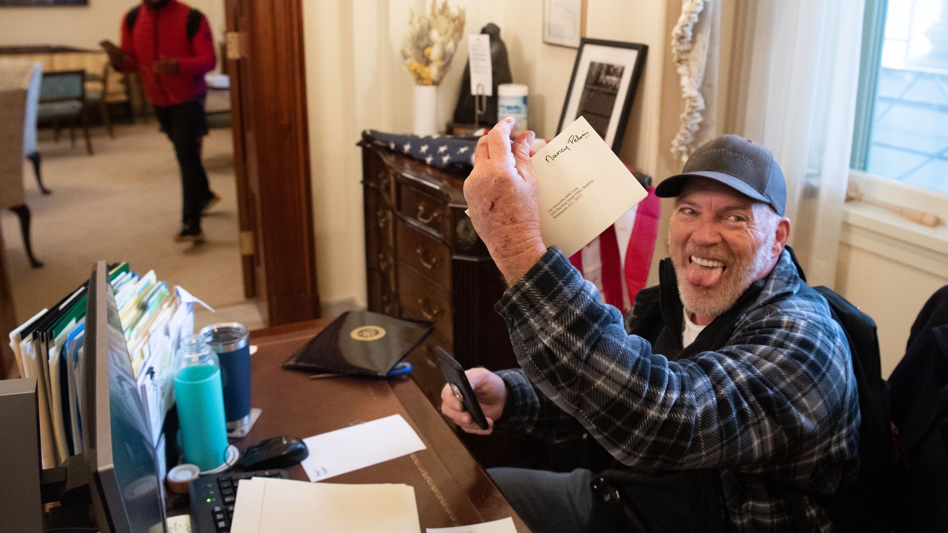 Richard Barnett of Gravett holds a piece of mail as he sits inside the office of U.S. Speaker of the House Nancy Pelosi in the U.S. Capitol on Jan. 6, 2021.