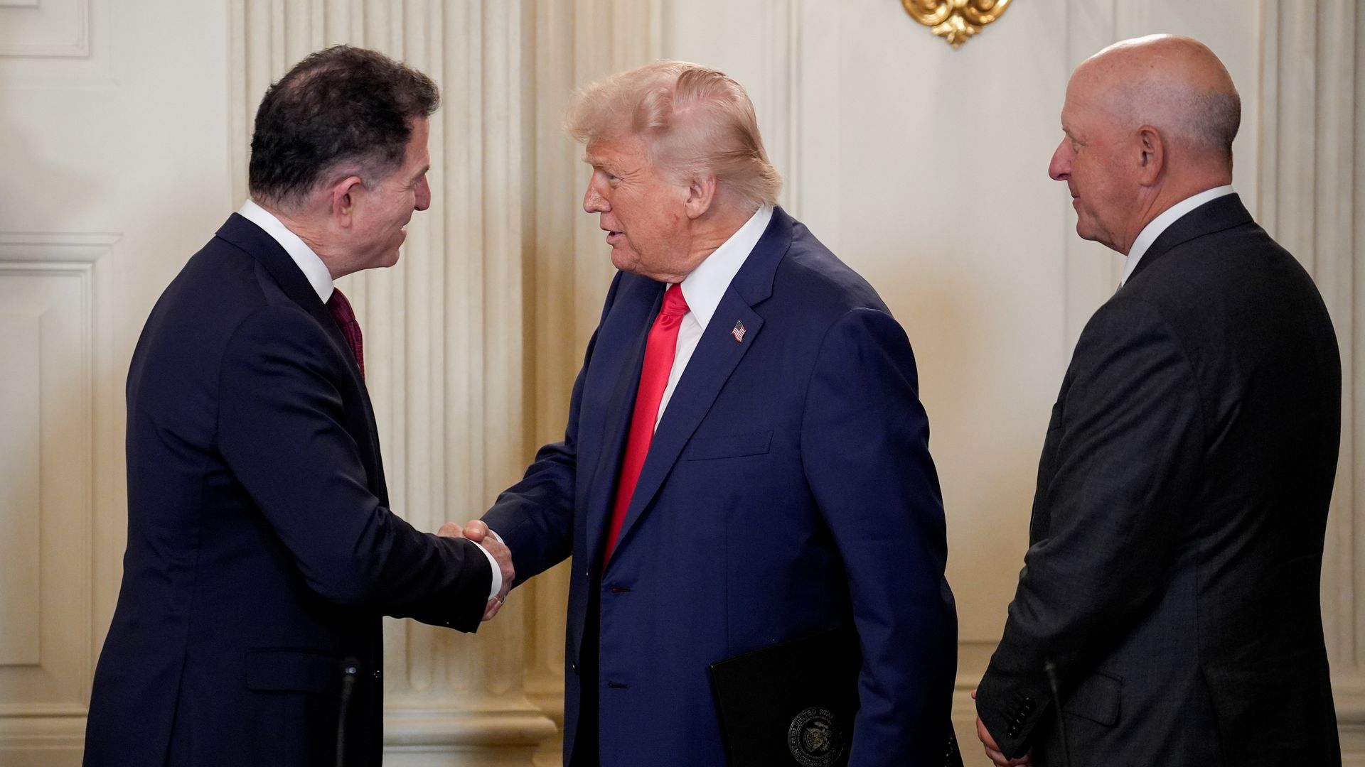 Michael Dell and Donald Trump, in suits, shake hands at the White House. 