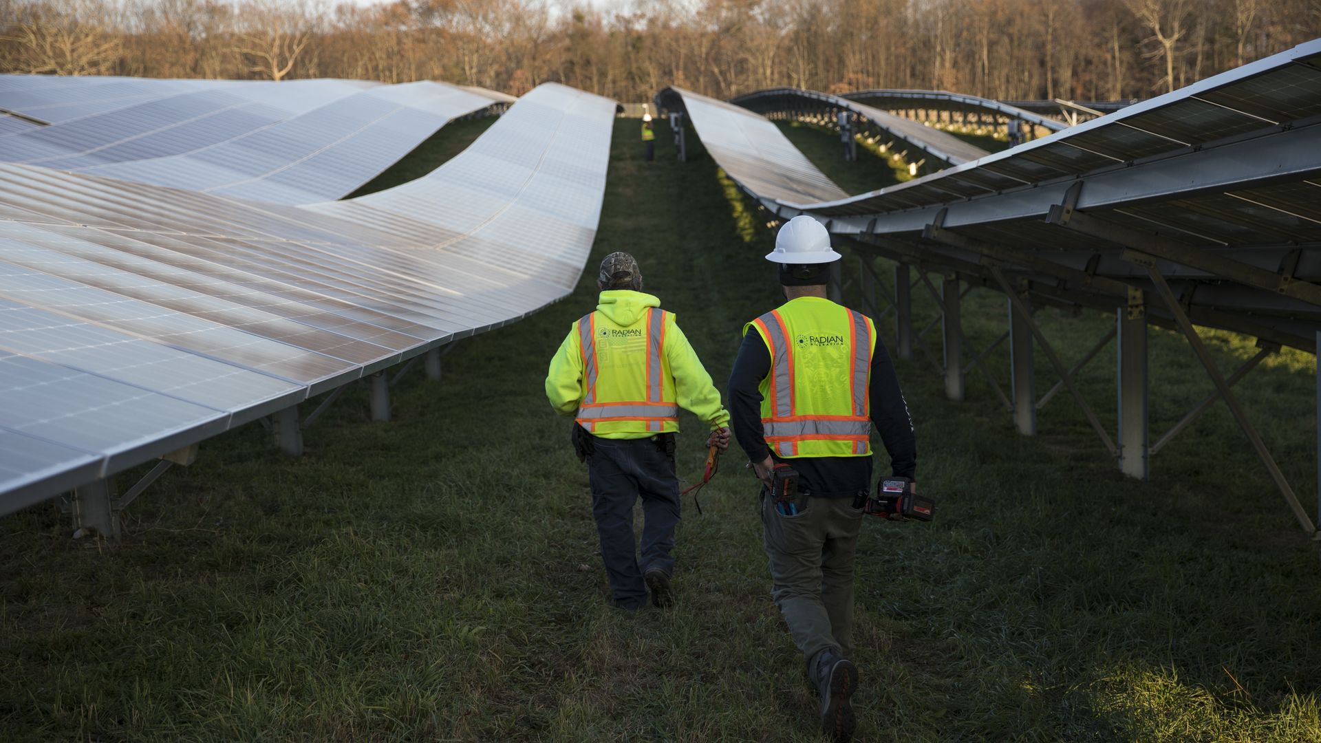 Employees from a Radian Generation's operations and maintenance team change out a faulty solar inverter along a row of solar panels