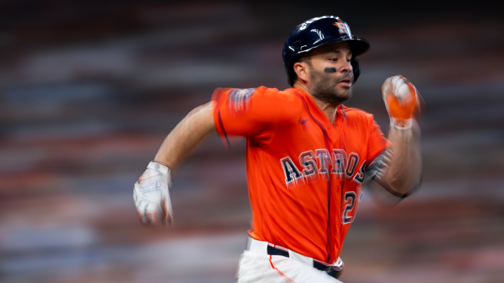 Photo of a man in an orange Astros jersey running. Blurred background