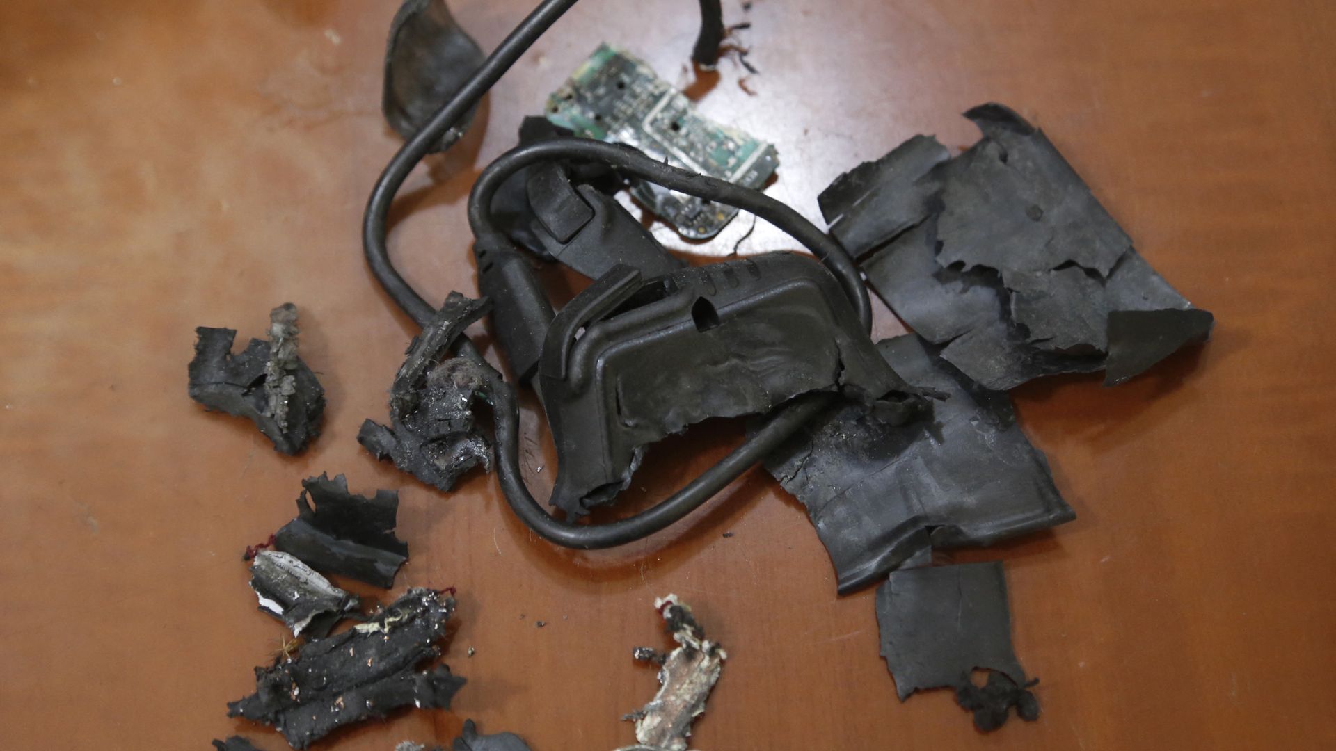 The remains of exploded pagers, black, are seen on a table, brown.