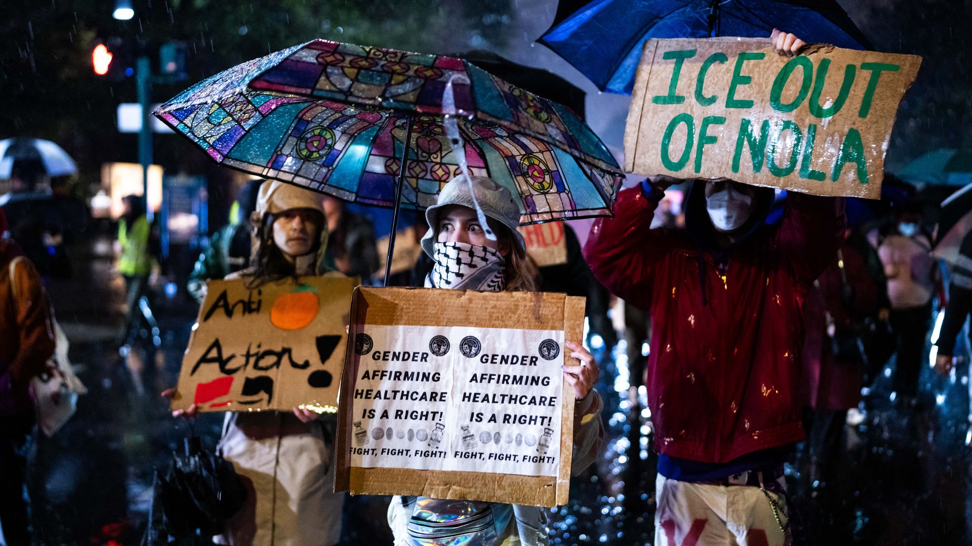 Protesters stand in the rain with signs saying things like "ICE out of NOLA." 